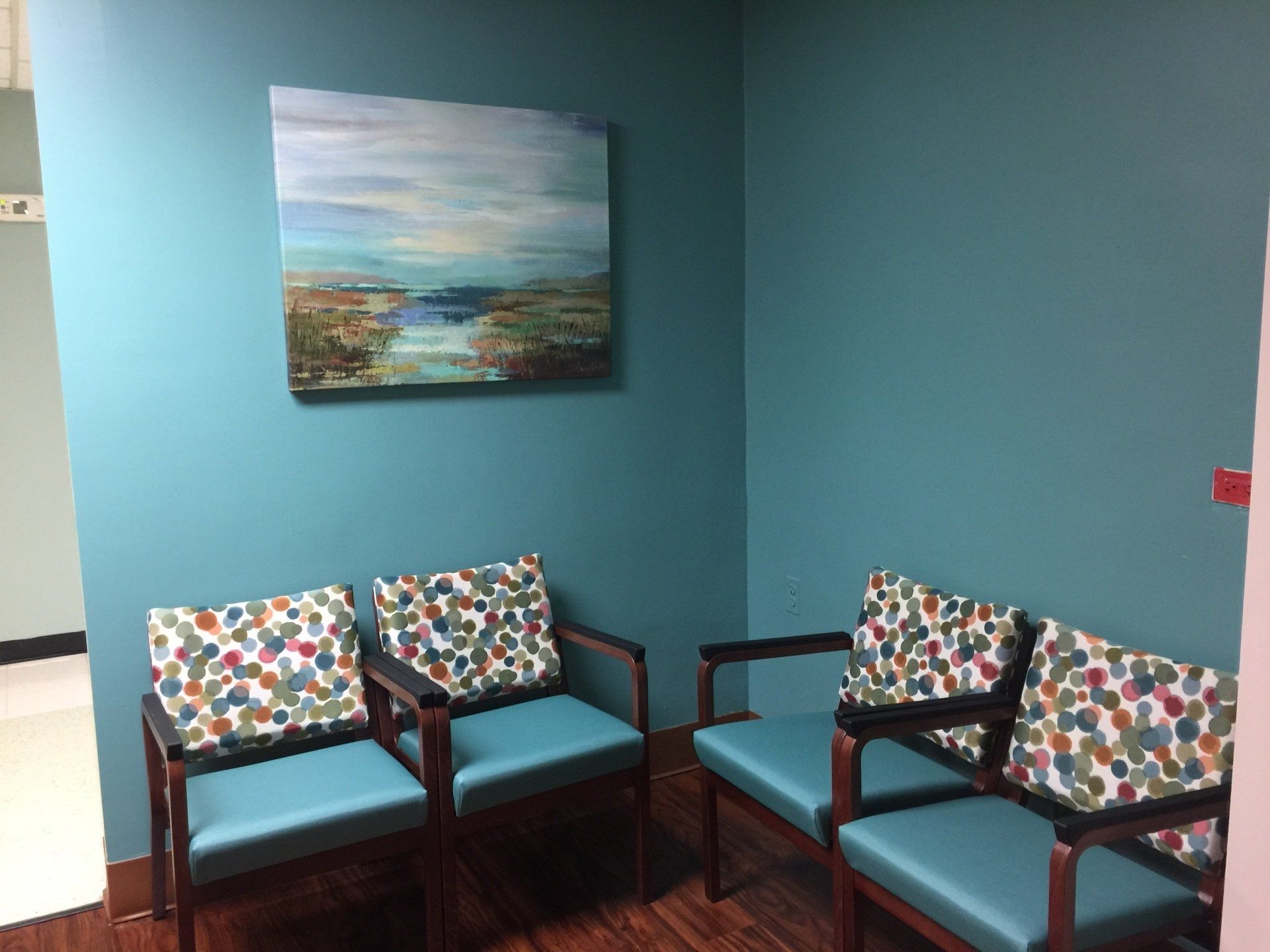 A waiting room with chairs and a painting on the wall