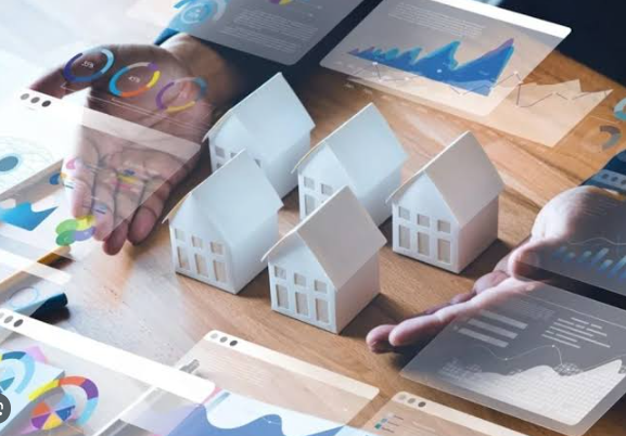 Hands discussing white house models over charts and graphs on a desk