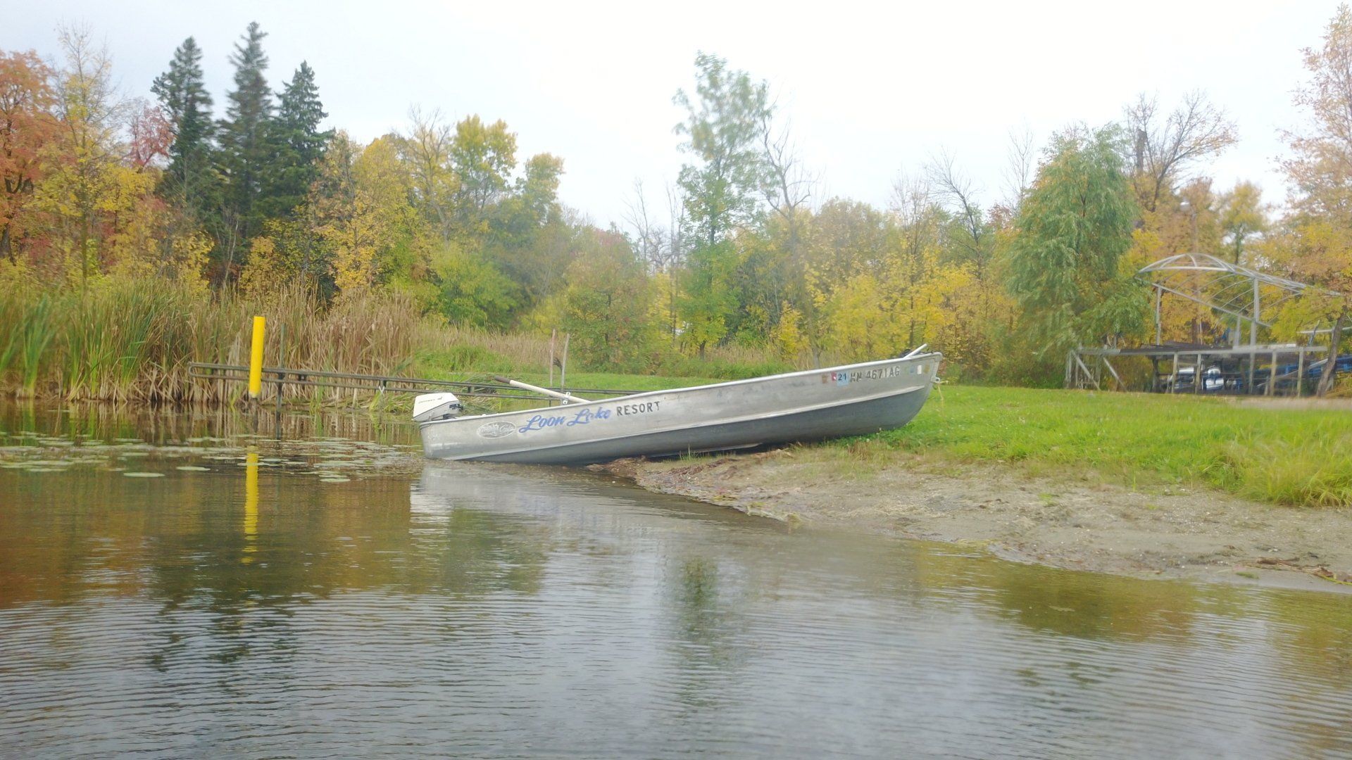 A boat is sitting on the shore of a lake.