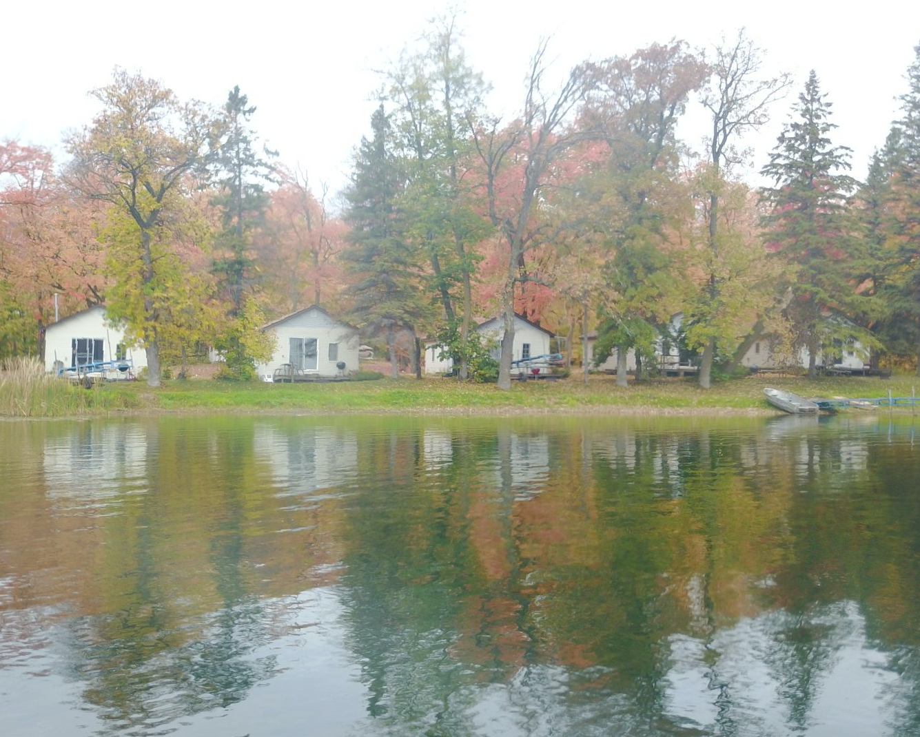 A row of houses sits on the shore of a lake surrounded by trees.