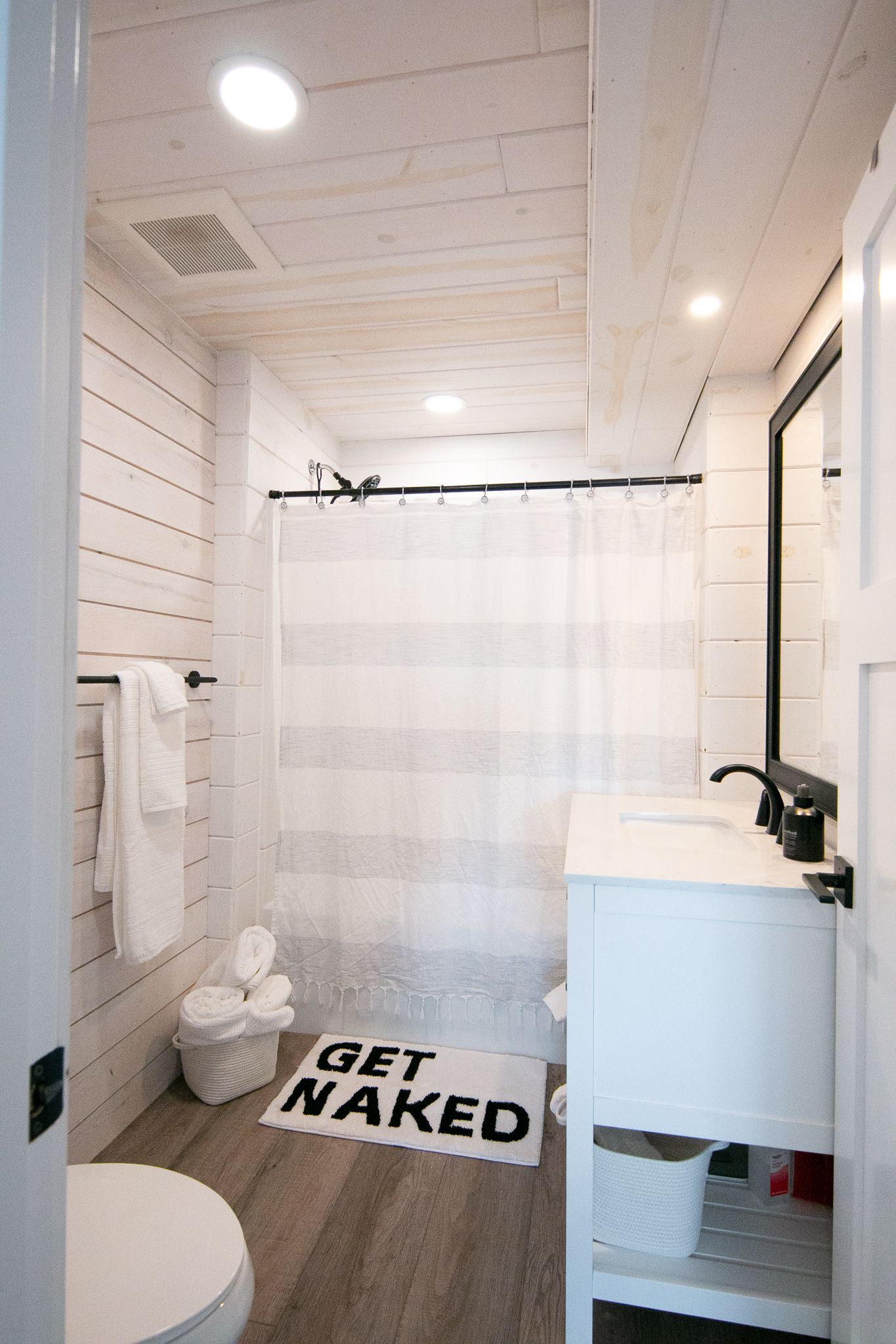 White and gray bathroom featuring a shower, sink, and toilet.