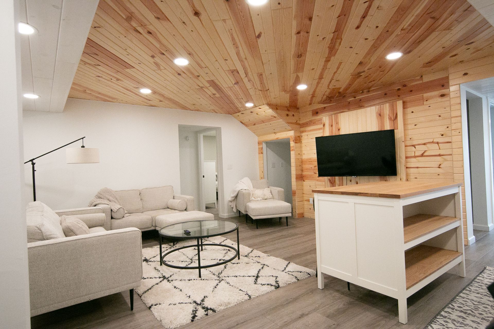 A living room with a wooden ceiling and a flat screen tv.