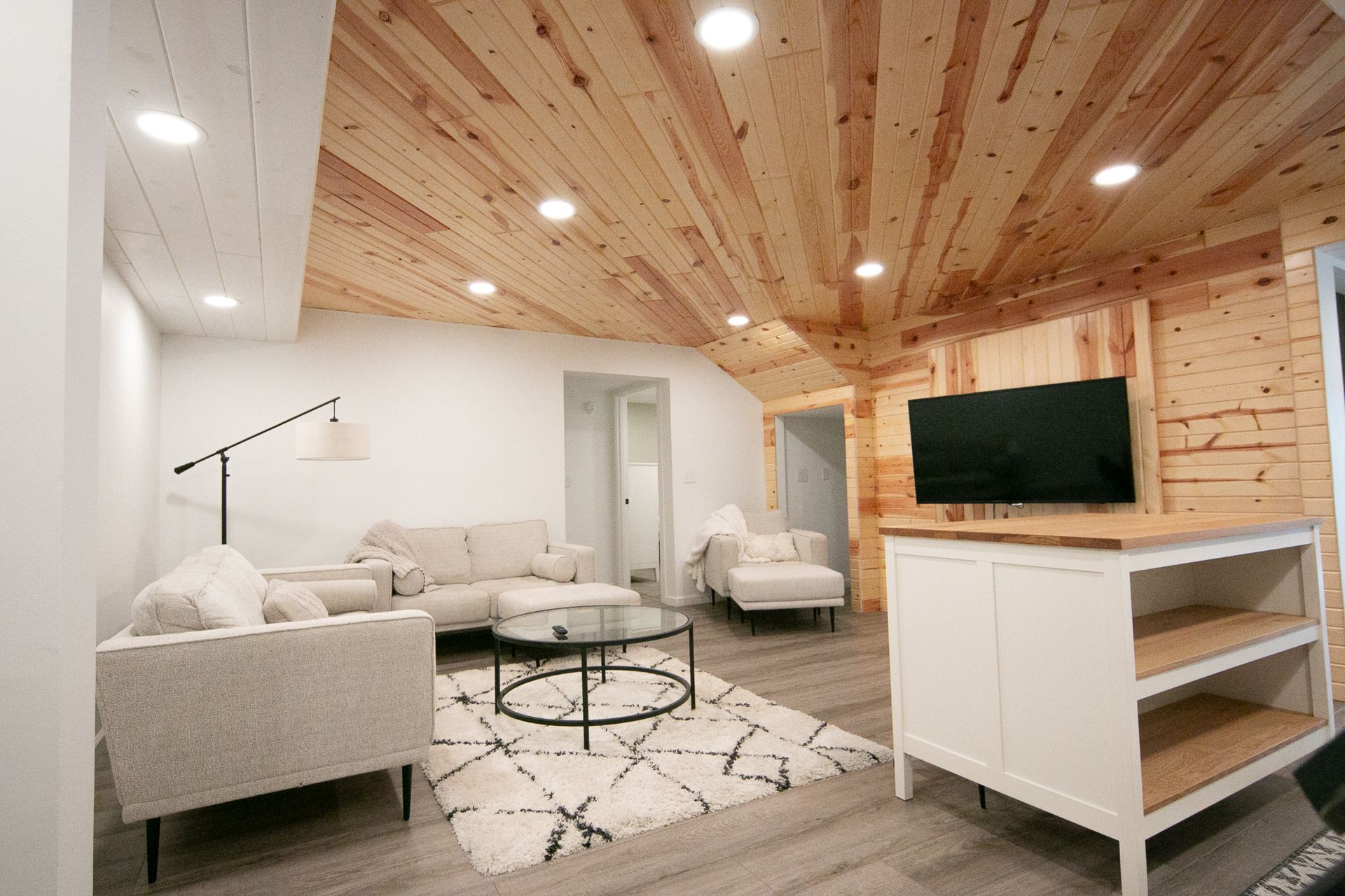 A living room with a couch , chairs , and a flat screen tv.