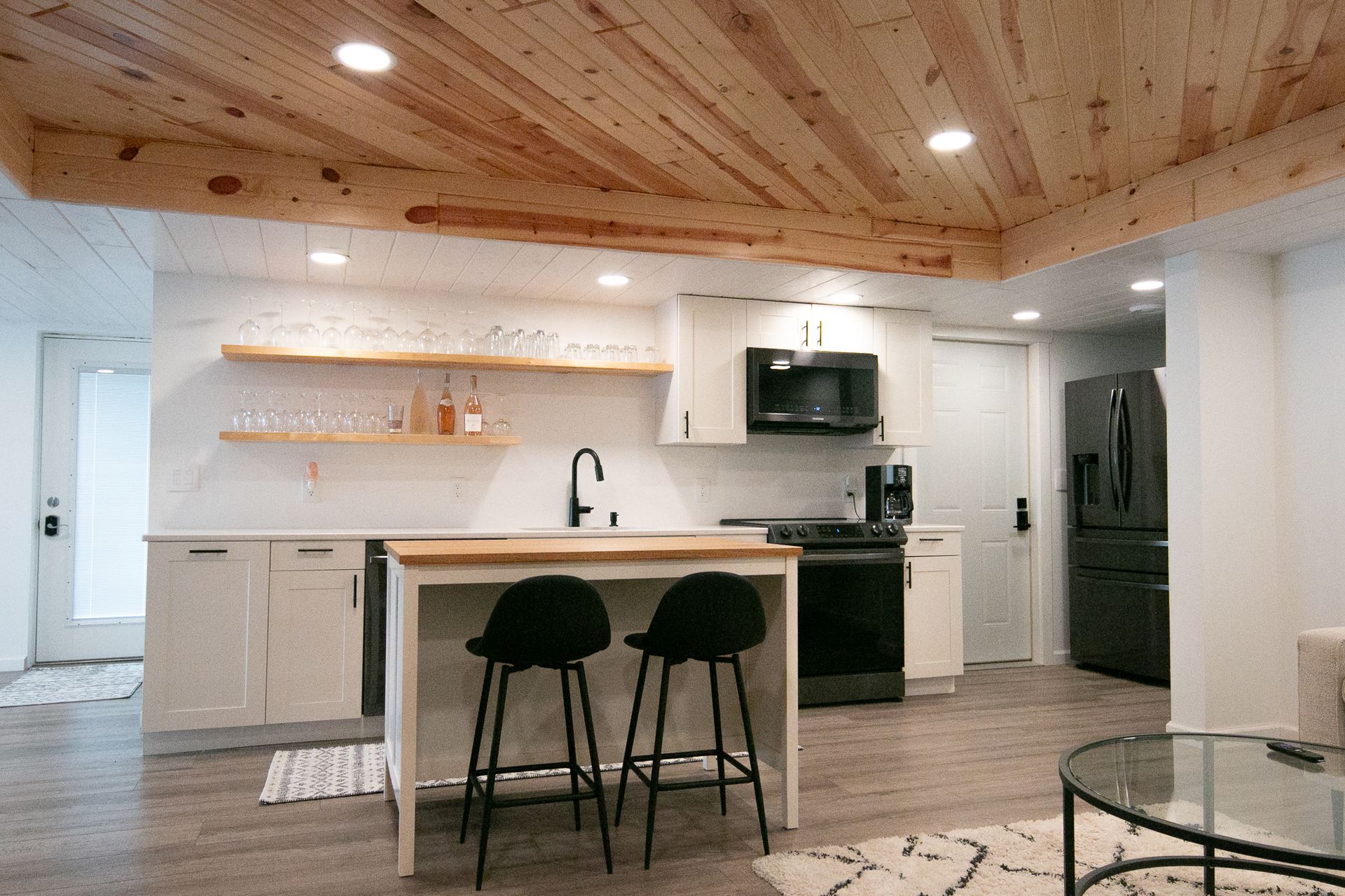 A kitchen with a wooden ceiling and a table and stools