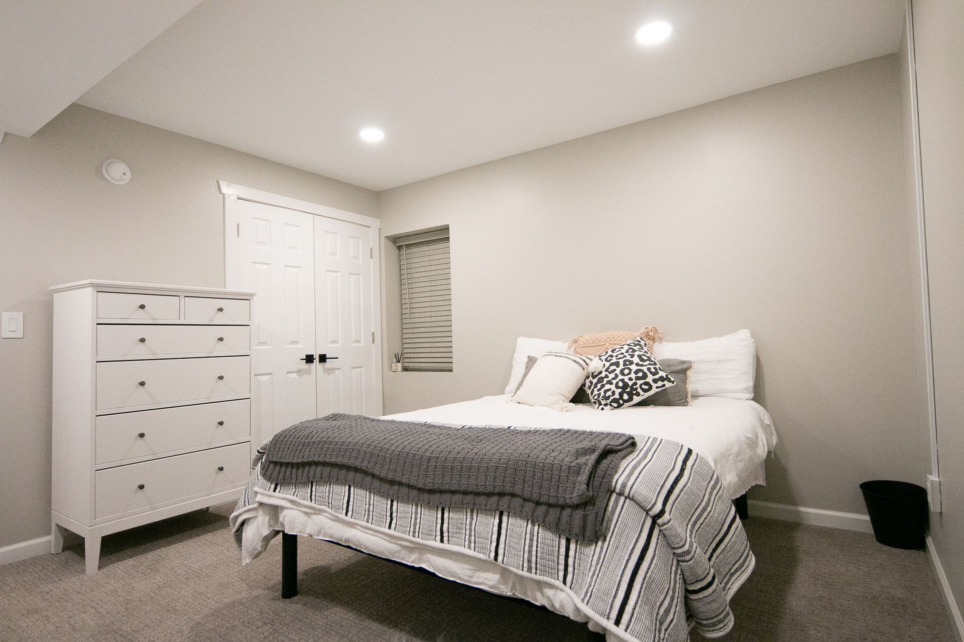 A bedroom with a bed , dresser , and window.