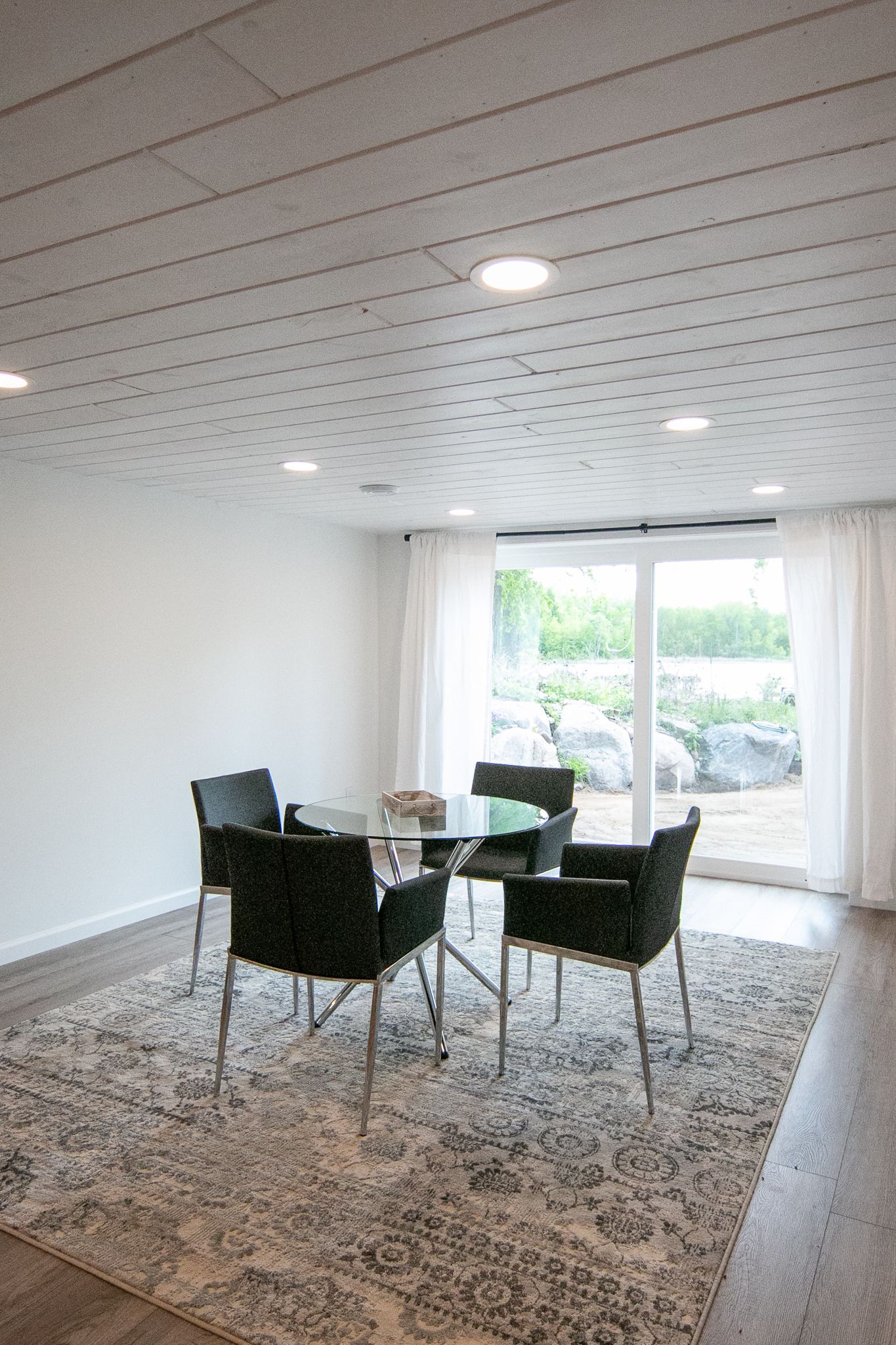 A dining room with a table and chairs and a rug.