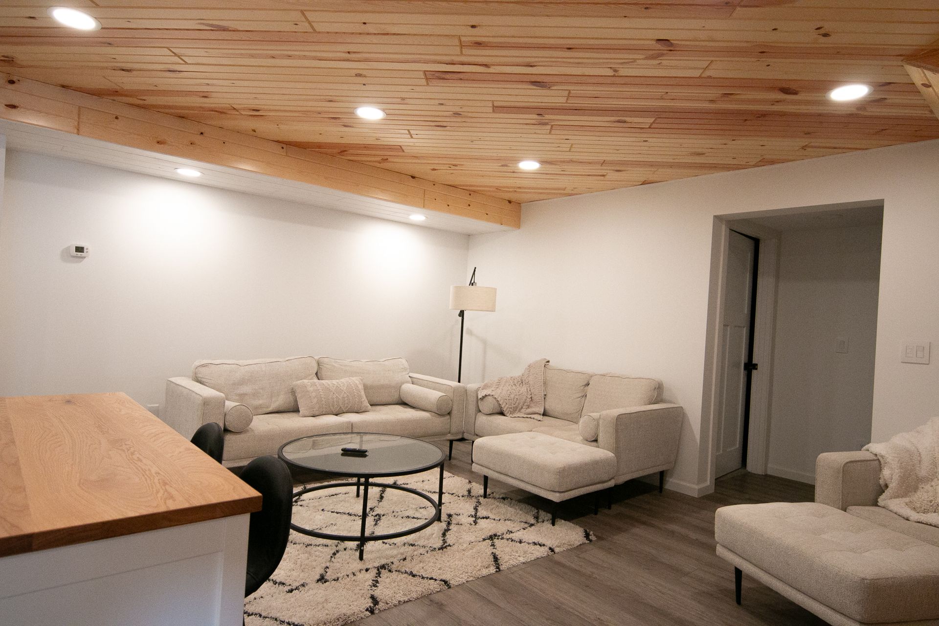 A living room with a couch , chair , coffee table and wooden ceiling.