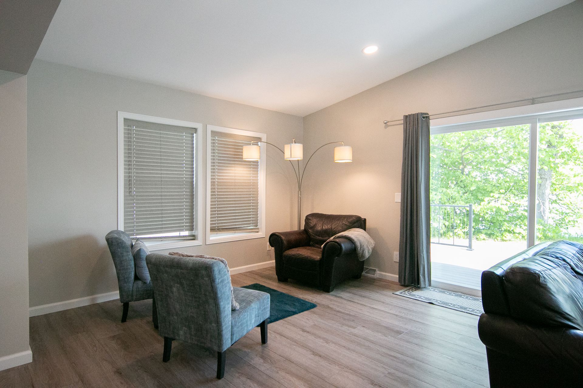 A living room with a couch , chairs , and a sliding glass door.