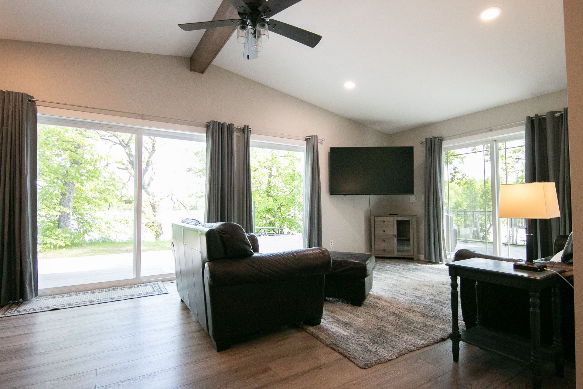 A living room with a ceiling fan , sliding glass doors , a couch and a flat screen tv.