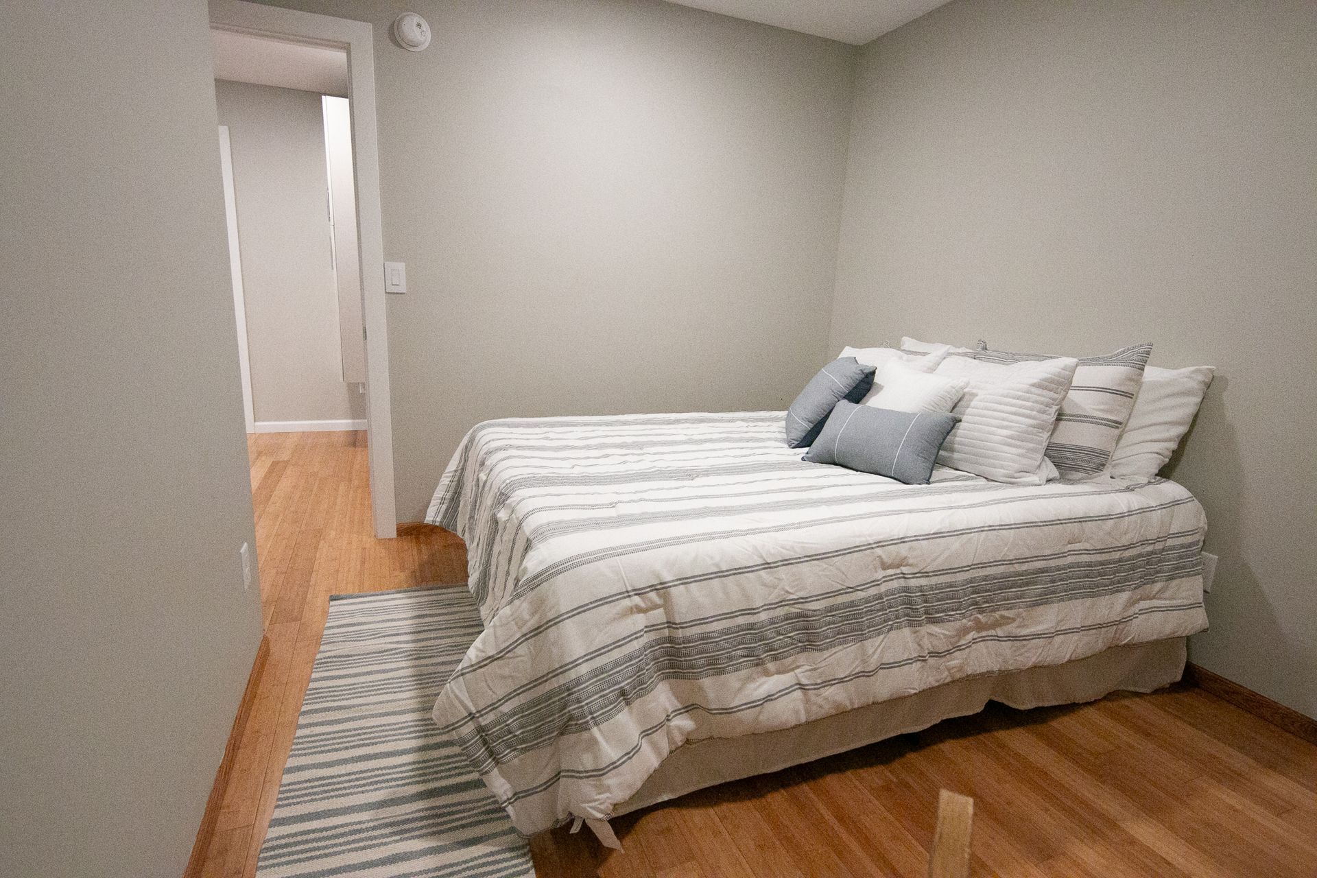 A bedroom with a bed and a rug on the floor.