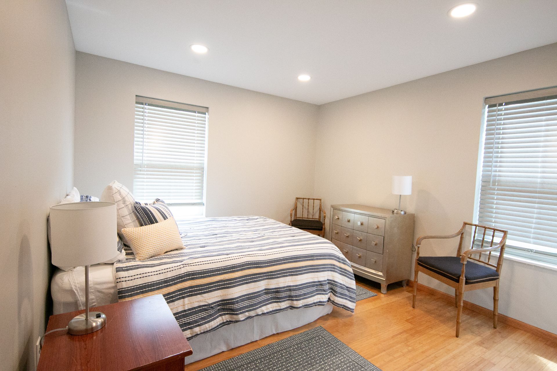 A bedroom with a bed , nightstand , chair and dresser.