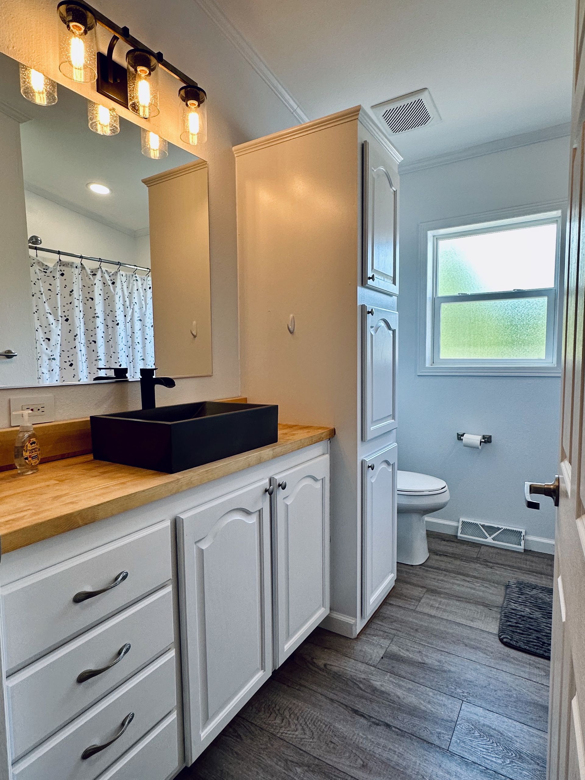 A bathroom with a sink , toilet and mirror.
