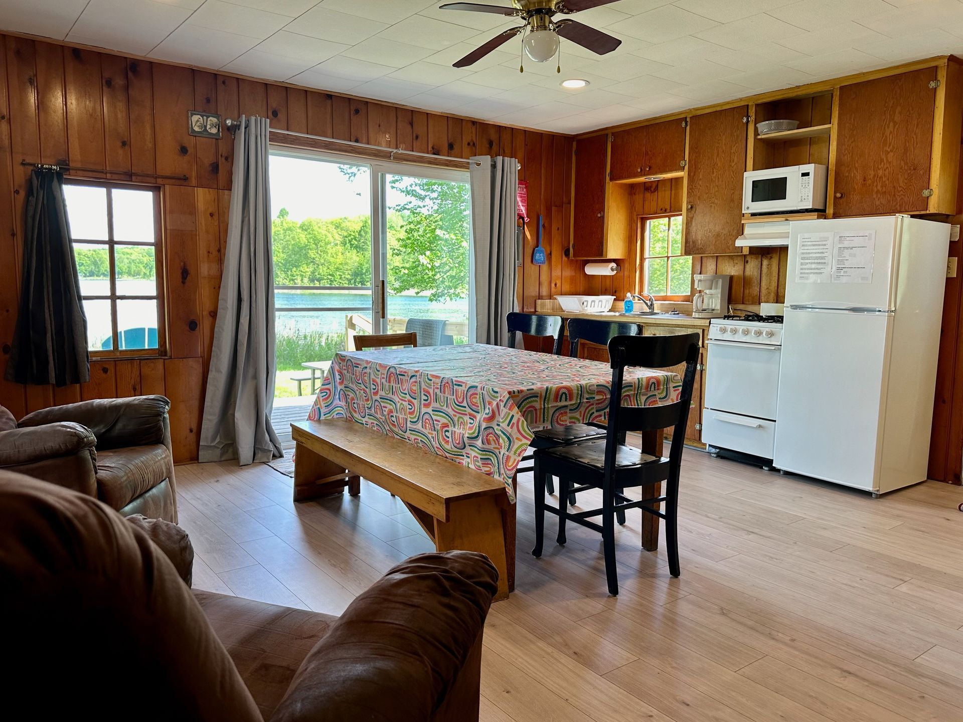 A living room with a table , chairs , and a refrigerator.
