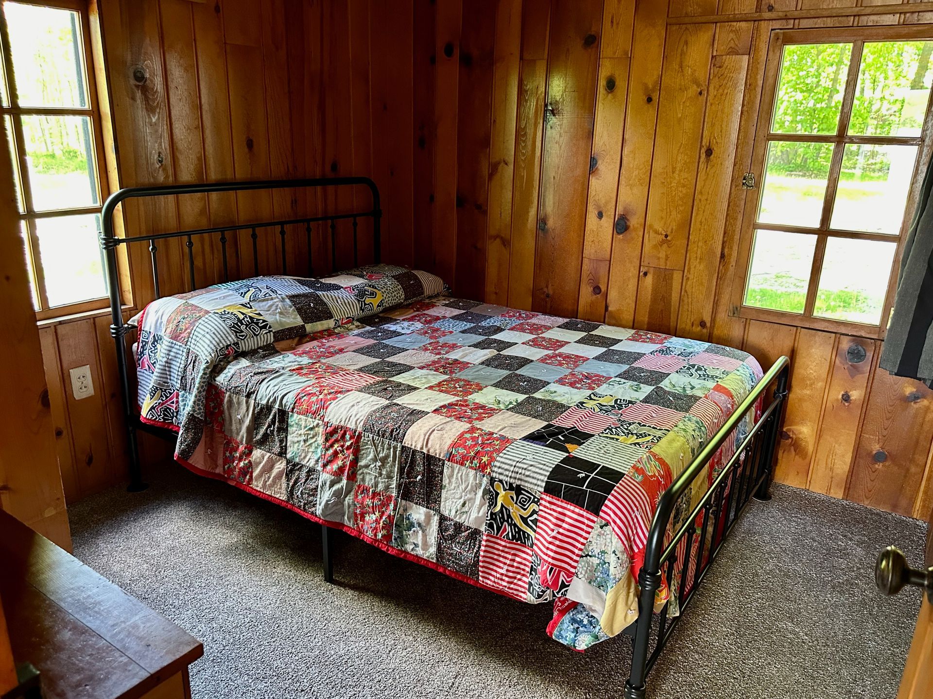 A bedroom with a bed and a window with a quilt on it.