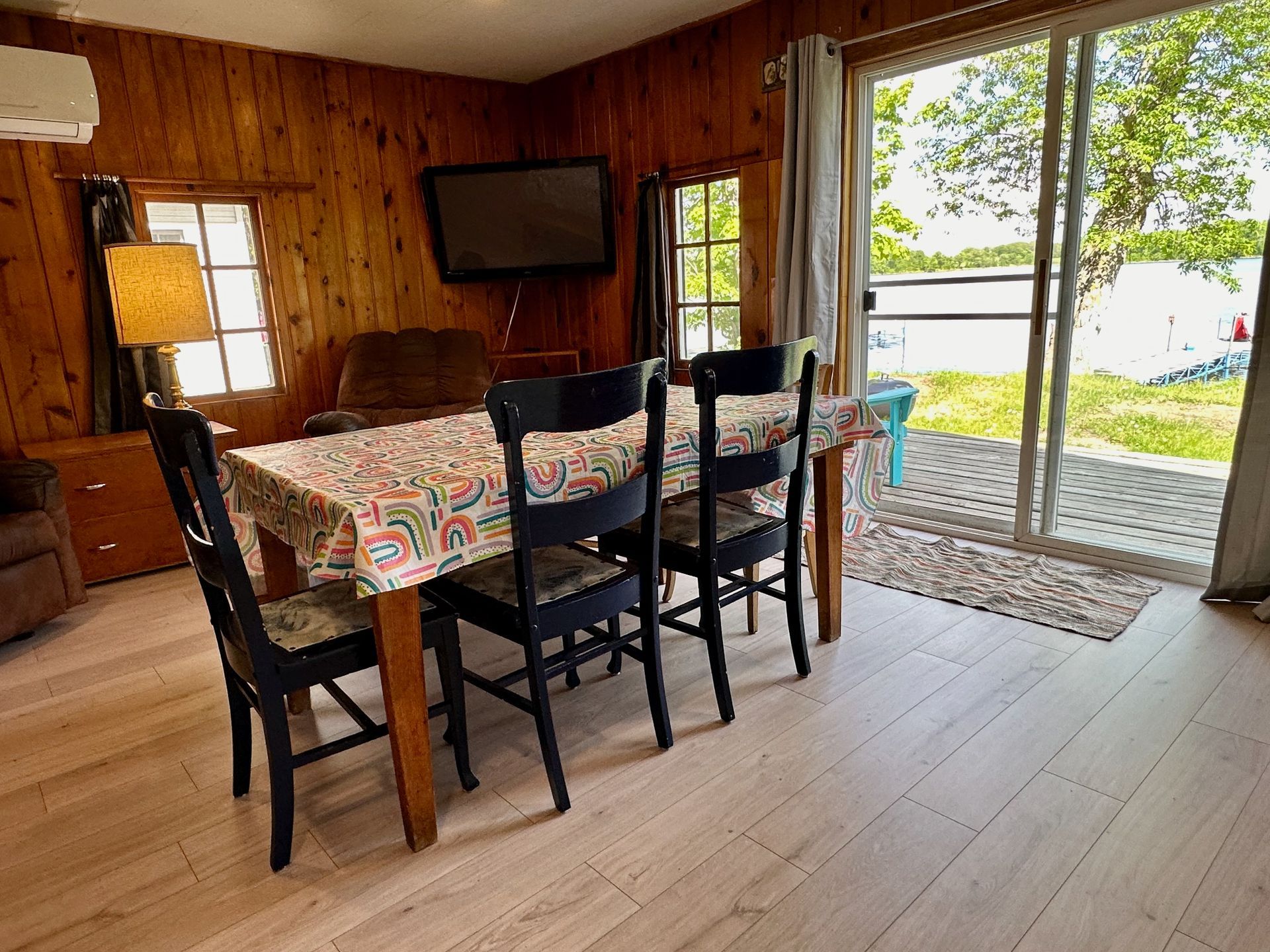 A dining room table and chairs in a cabin with a sliding glass door.