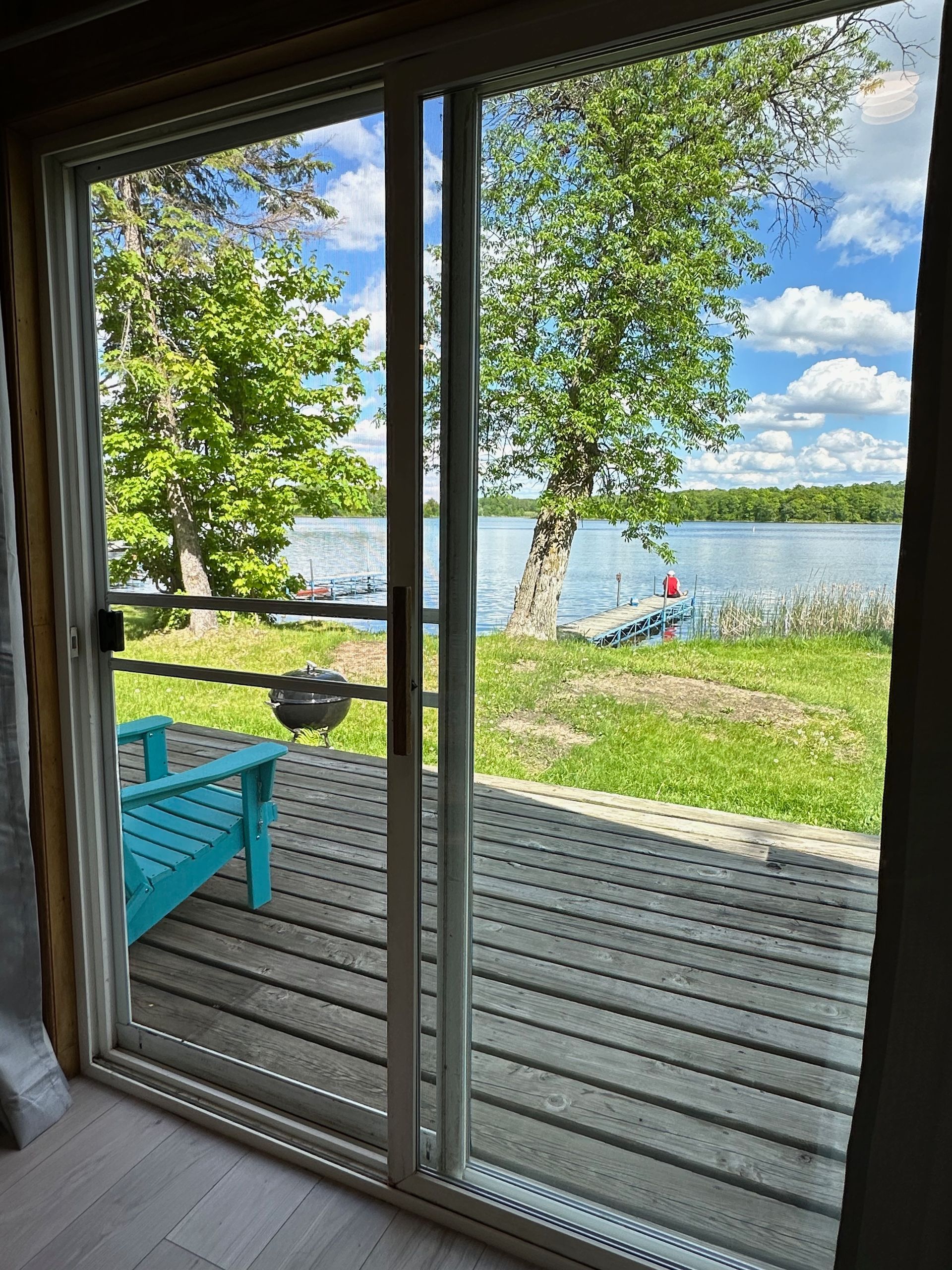 A sliding glass door leading to a deck overlooking a lake.