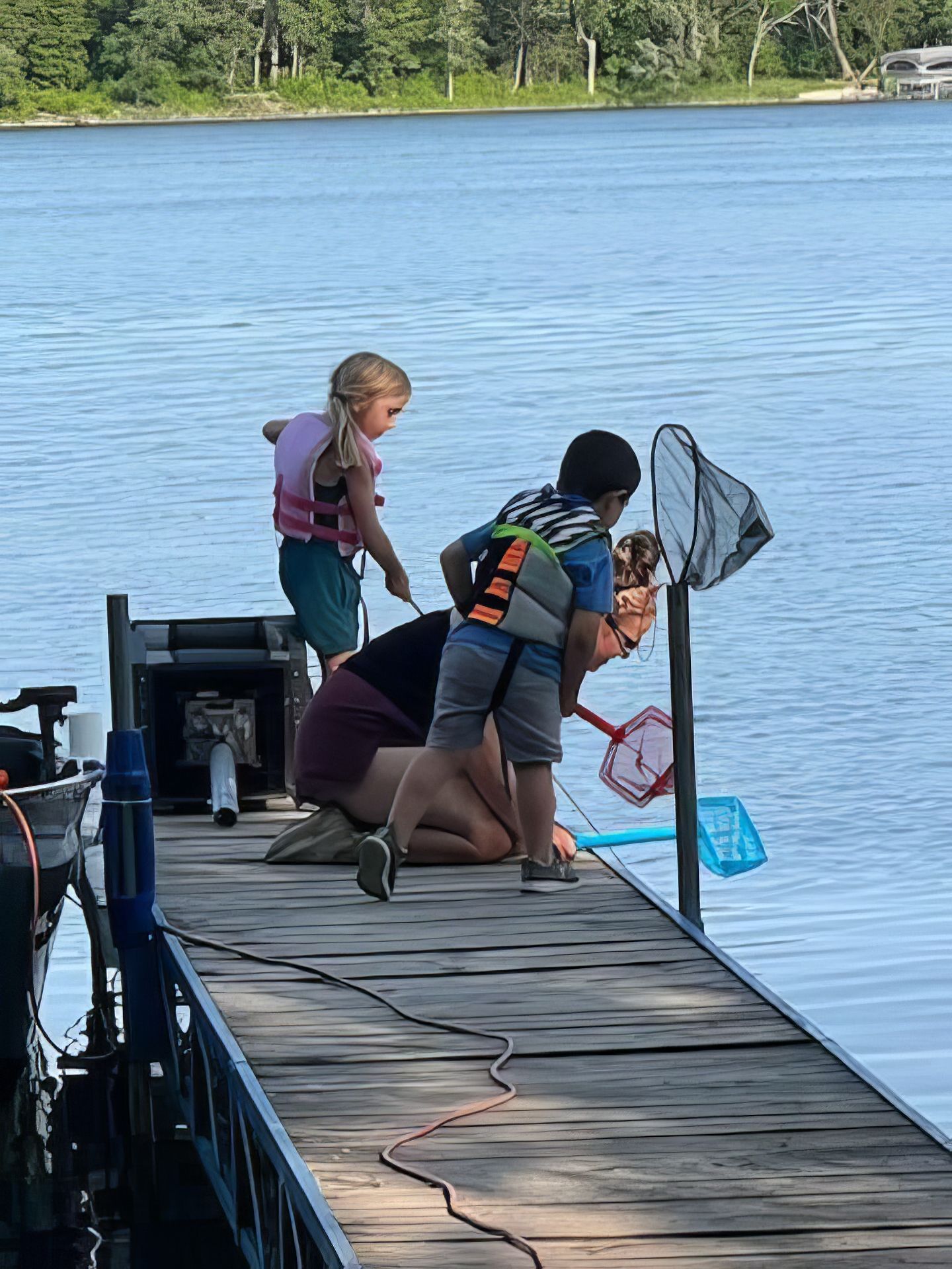 A woman and two children are fishing on a dock.