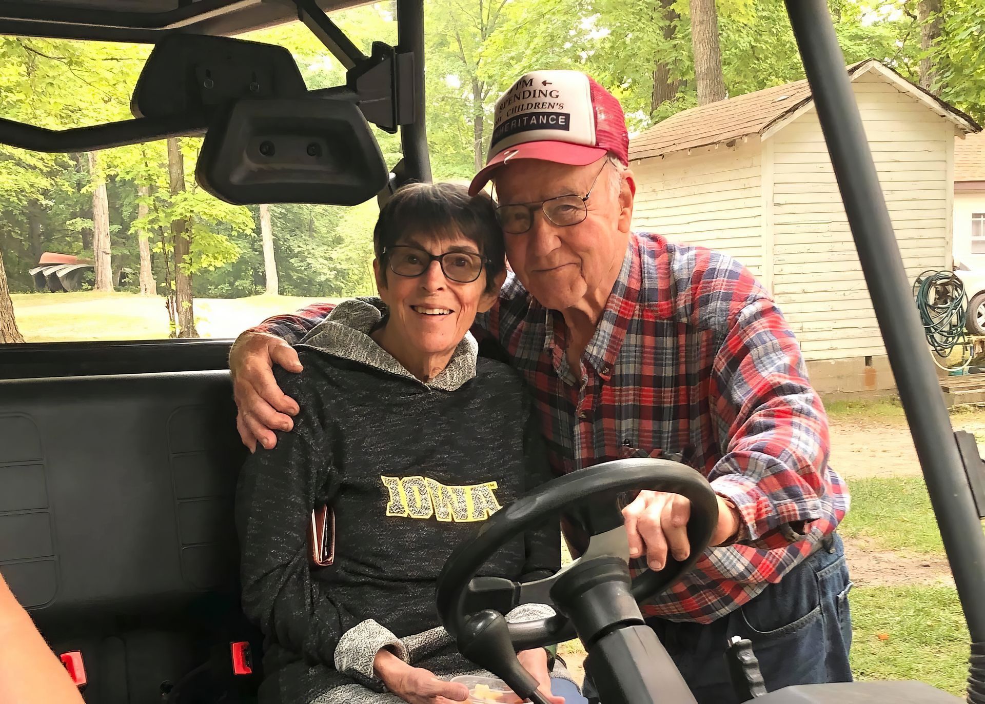 A man and a woman are sitting in a golf cart.