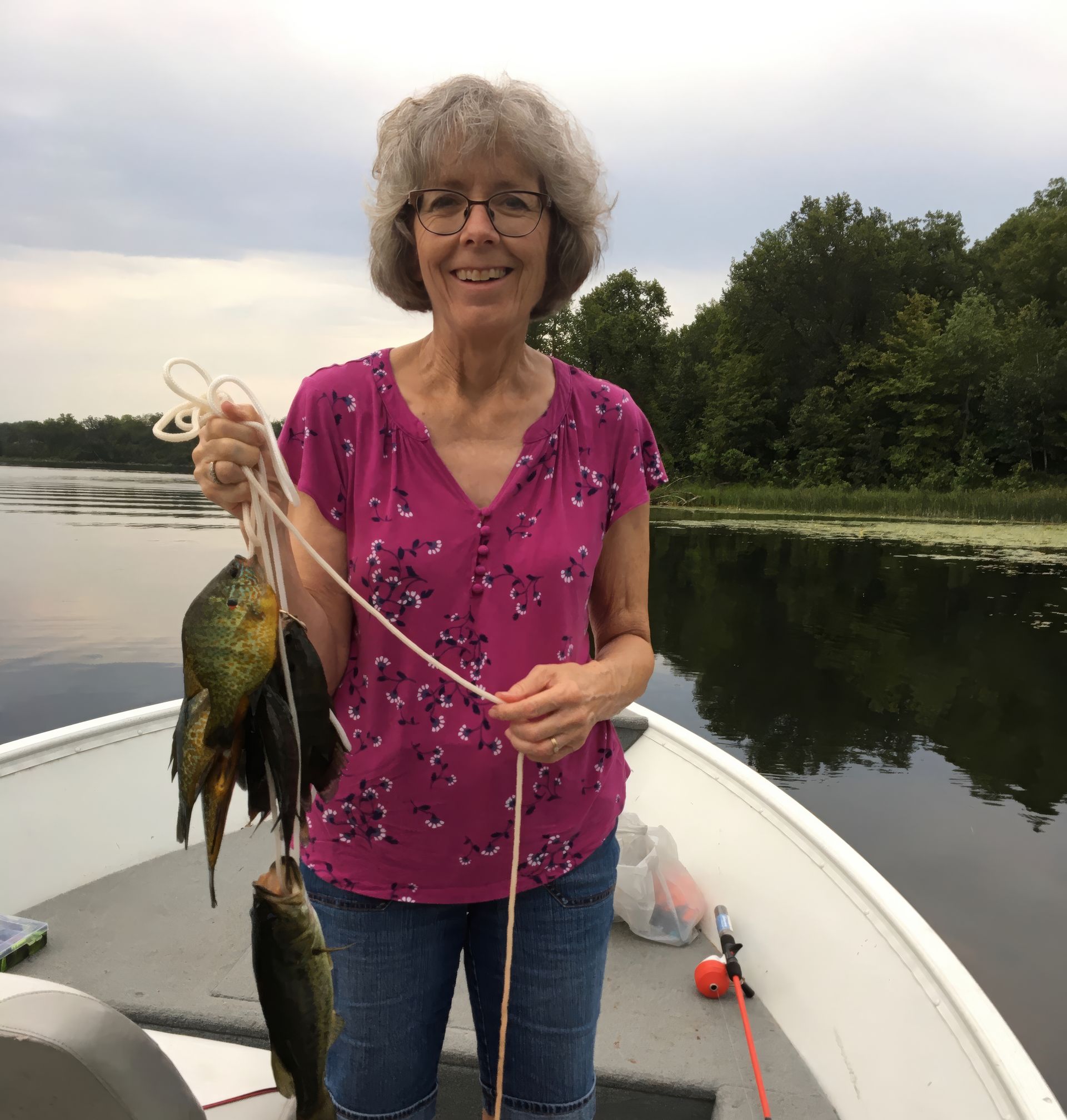 A woman is standing on a boat holding two fish