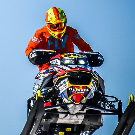 A man riding a snowmobile with the word fly on his shirt