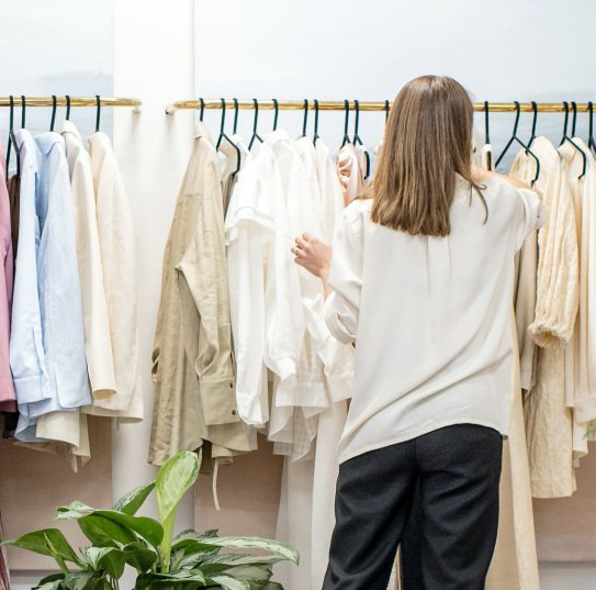 A woman is standing in front of a rack of clothes