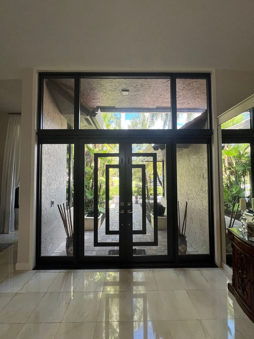 Black framed glass double doors with rectangular design; bright light through the doors.