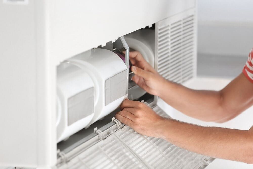 A Person Is Fixing An Air Conditioner With Their Hands — Allpower Electrical Wholesalers Pty Ltd In Cooktown, QLD
