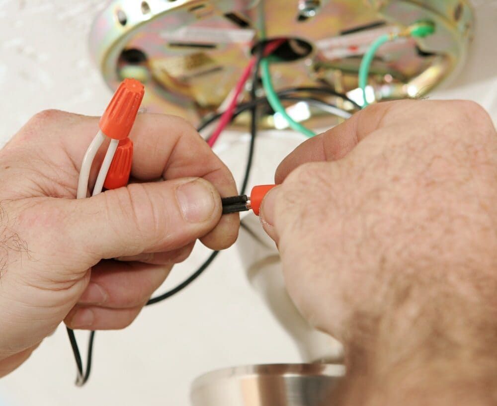 A Person Is Working On A Ceiling Fan With A Screwdriver — Allpower Electrical Wholesalers Pty Ltd In Weipa, QLD