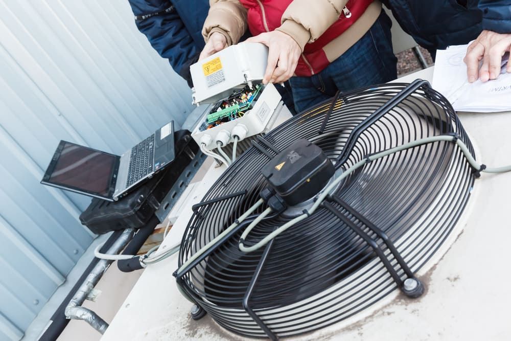 Two People Are Working On A Large Fan On A Table — Allpower Electrical Wholesalers Pty Ltd In Bungalow, QLD