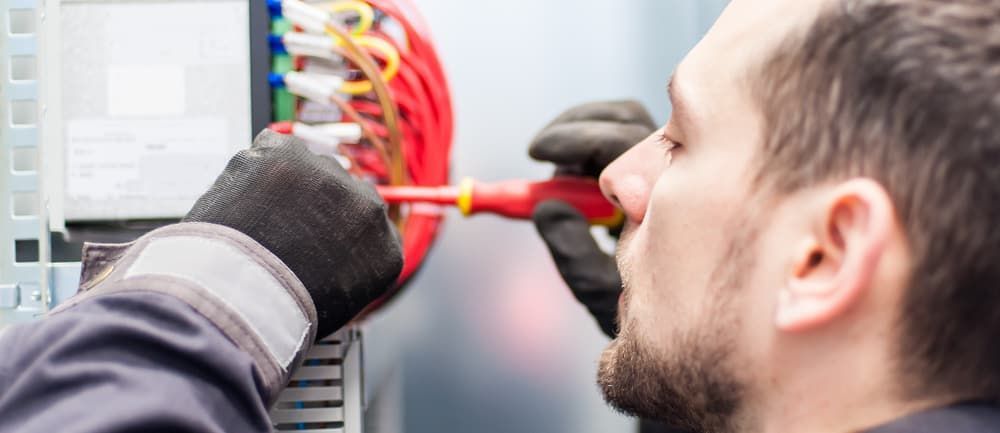 A Man Is Working On An Electrical Box With A Screwdriver — Allpower Electrical Wholesalers Pty Ltd In Bungalow, QLD