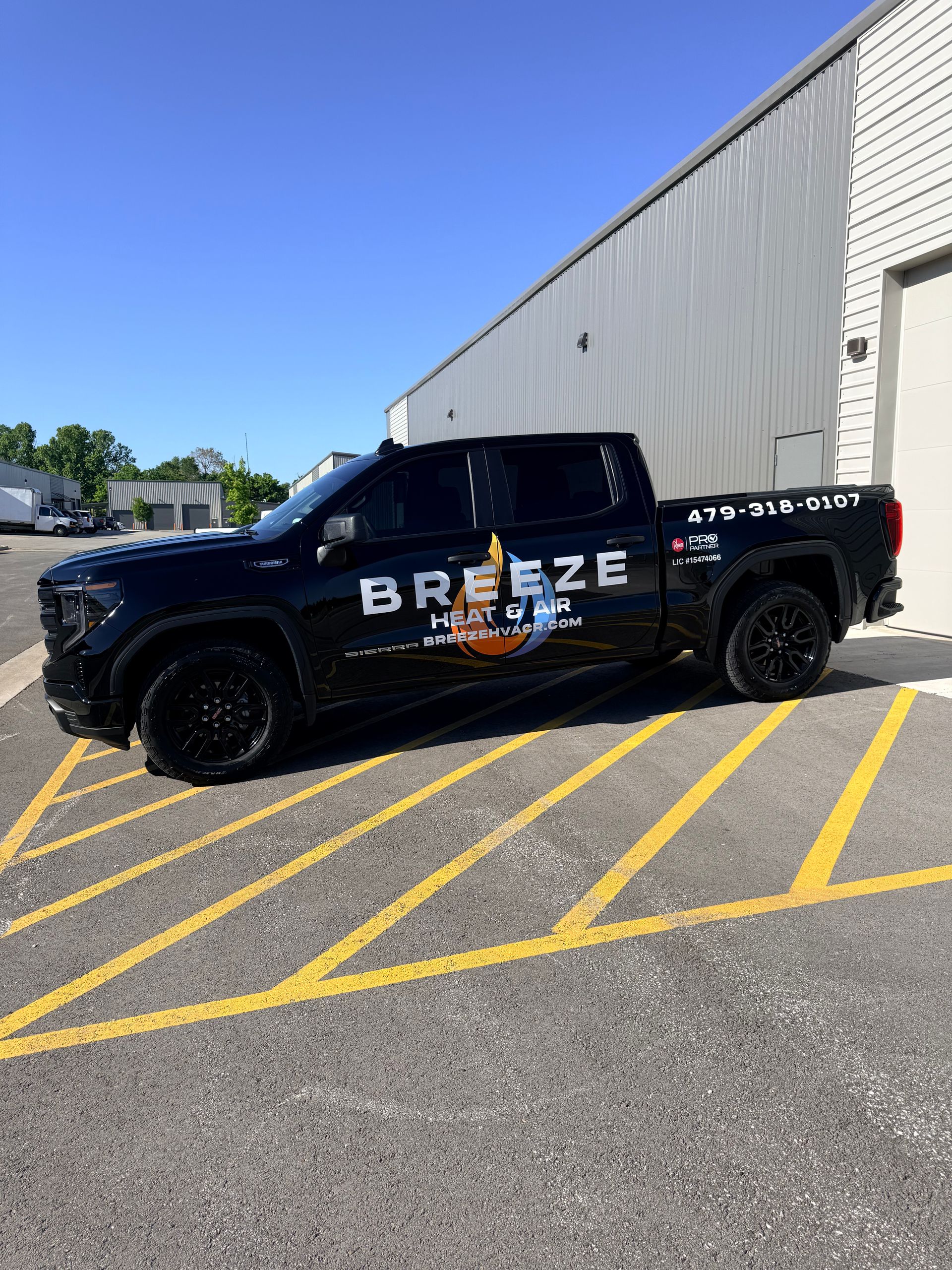 Black BREEZE pickup truck parked beside a white warehouse on yellow-striped pavement