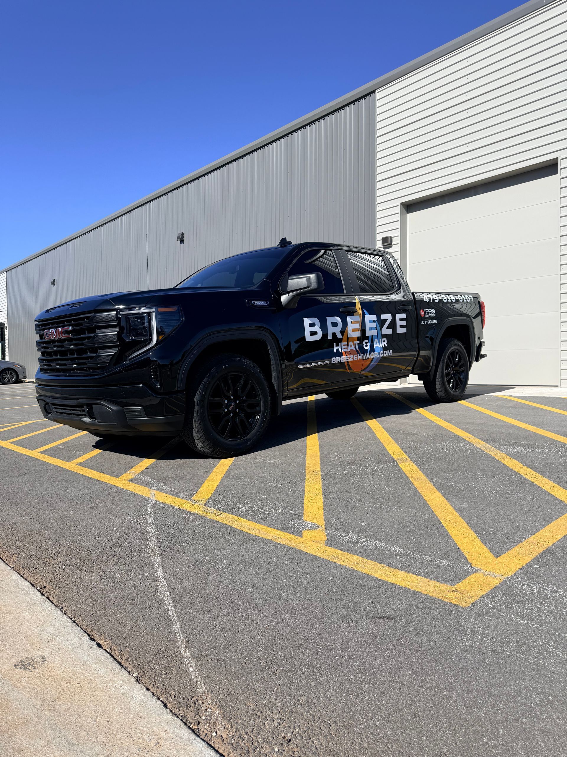 Black Breeze-branded pickup truck parked outside a warehouse on yellow-striped pavement