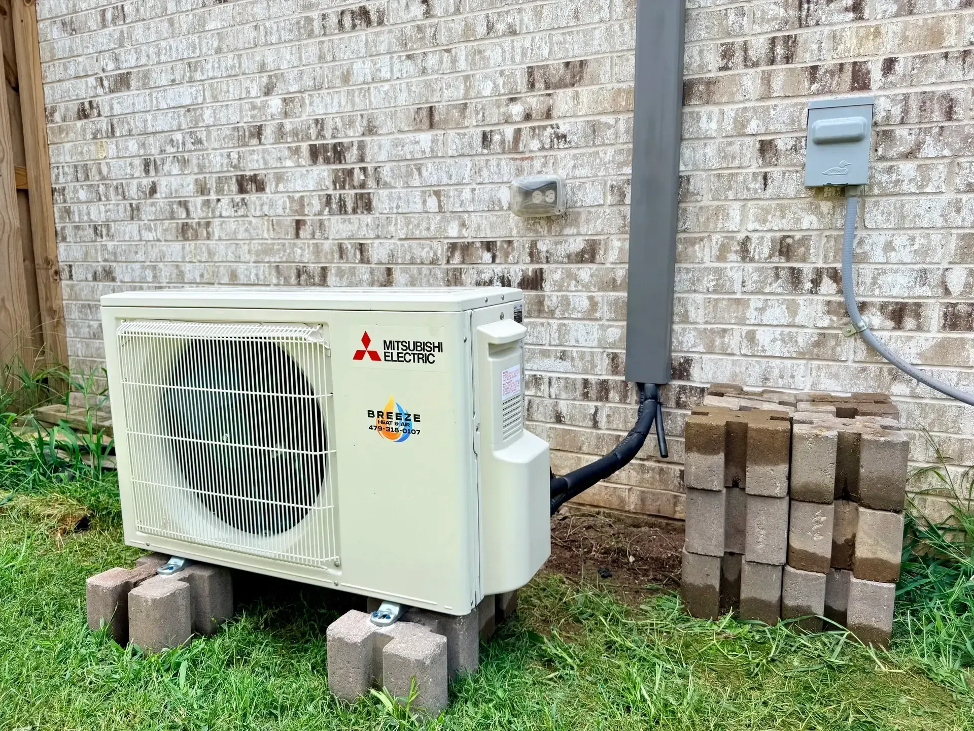 AC repair technician servicing air conditioner in Lowell AR home
