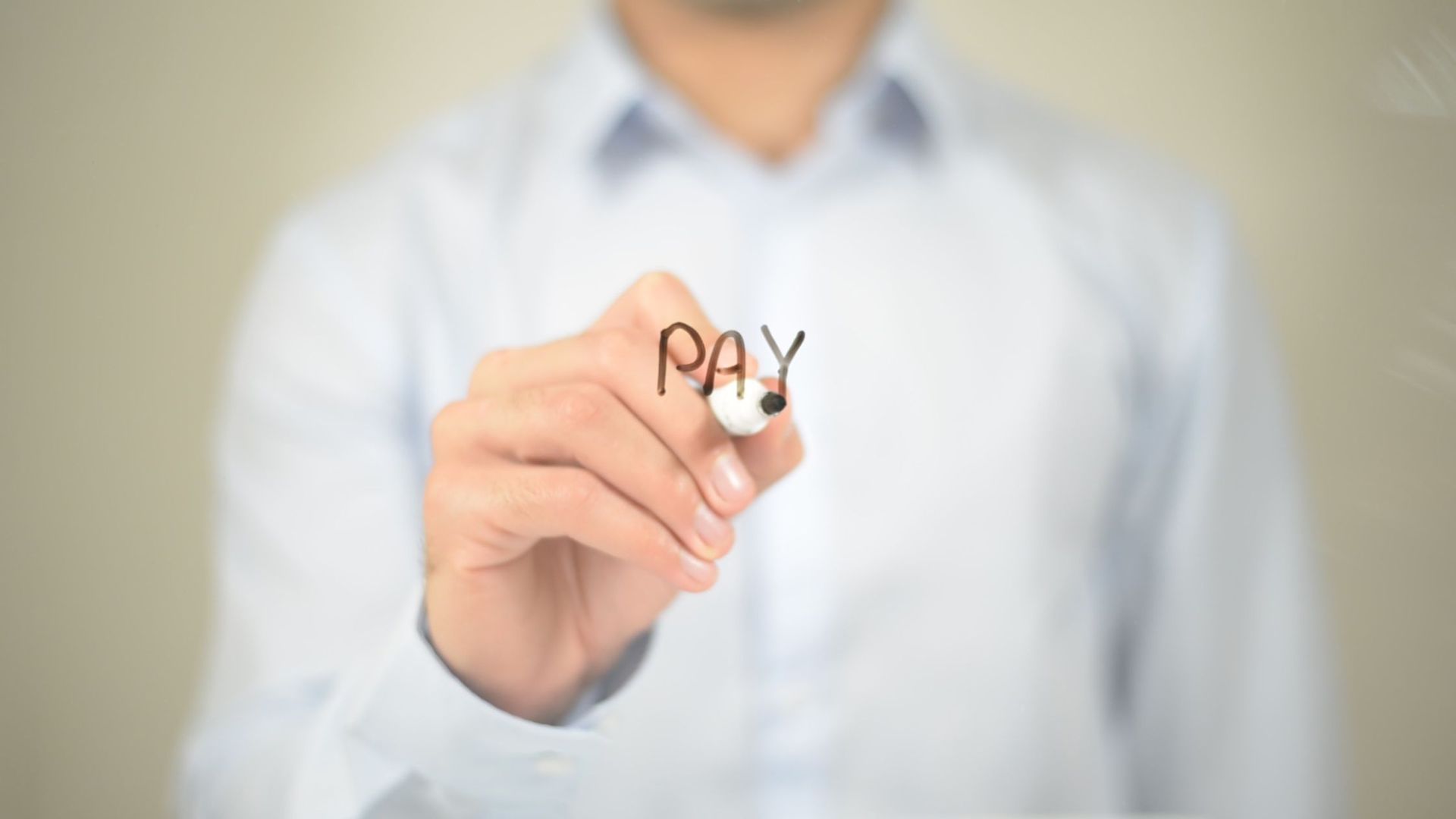 Person writing 'pay' on transparent surface