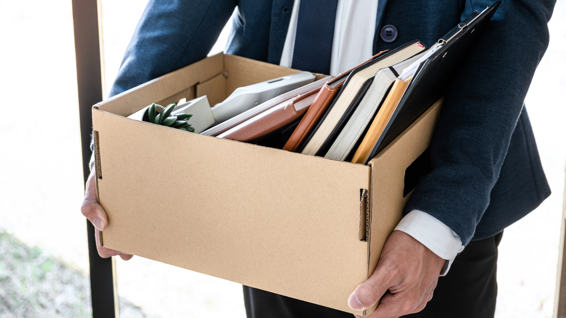 Person holding a box filled with work paperwork.