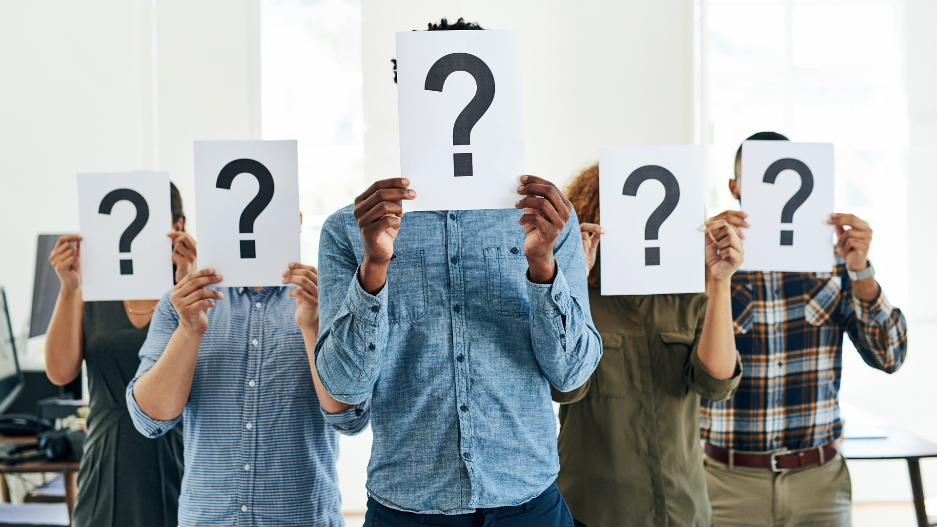 People holding papers with question marks over their faces.