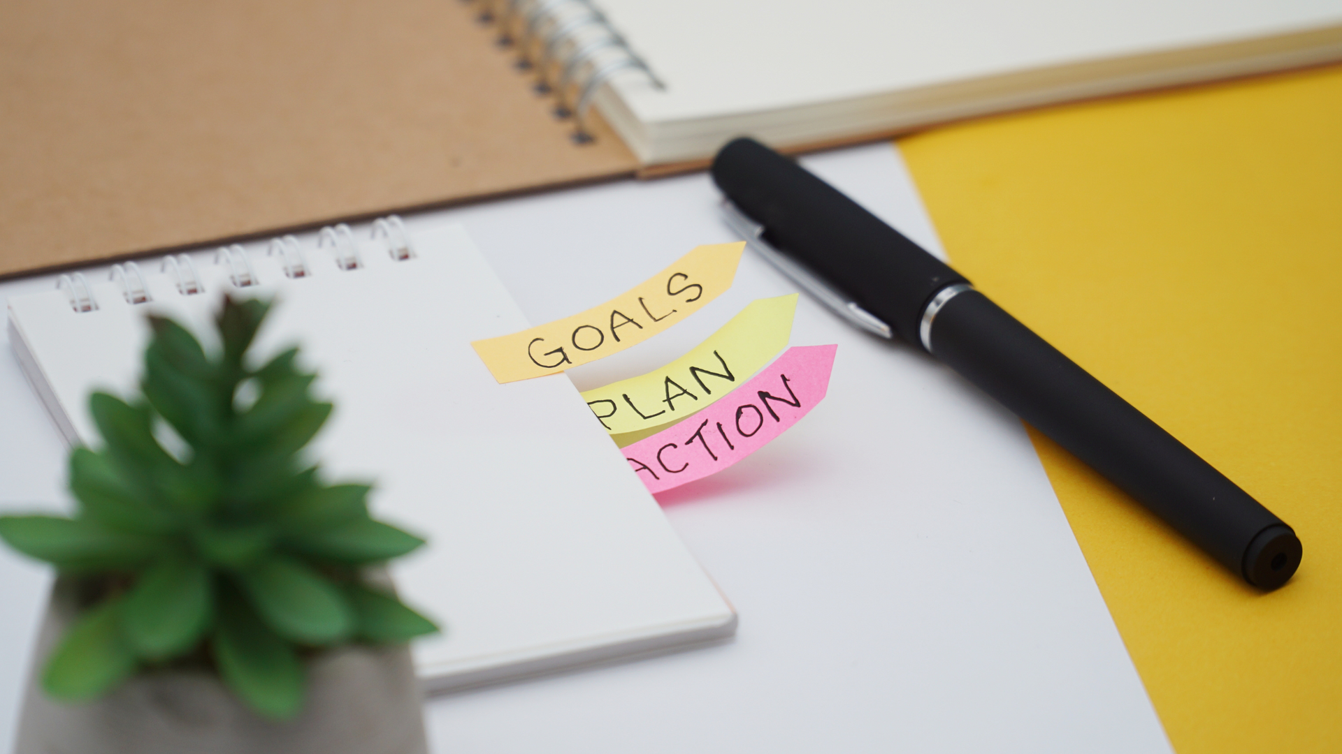 Note pad with tabs that read Goals, Plan, Action. 
