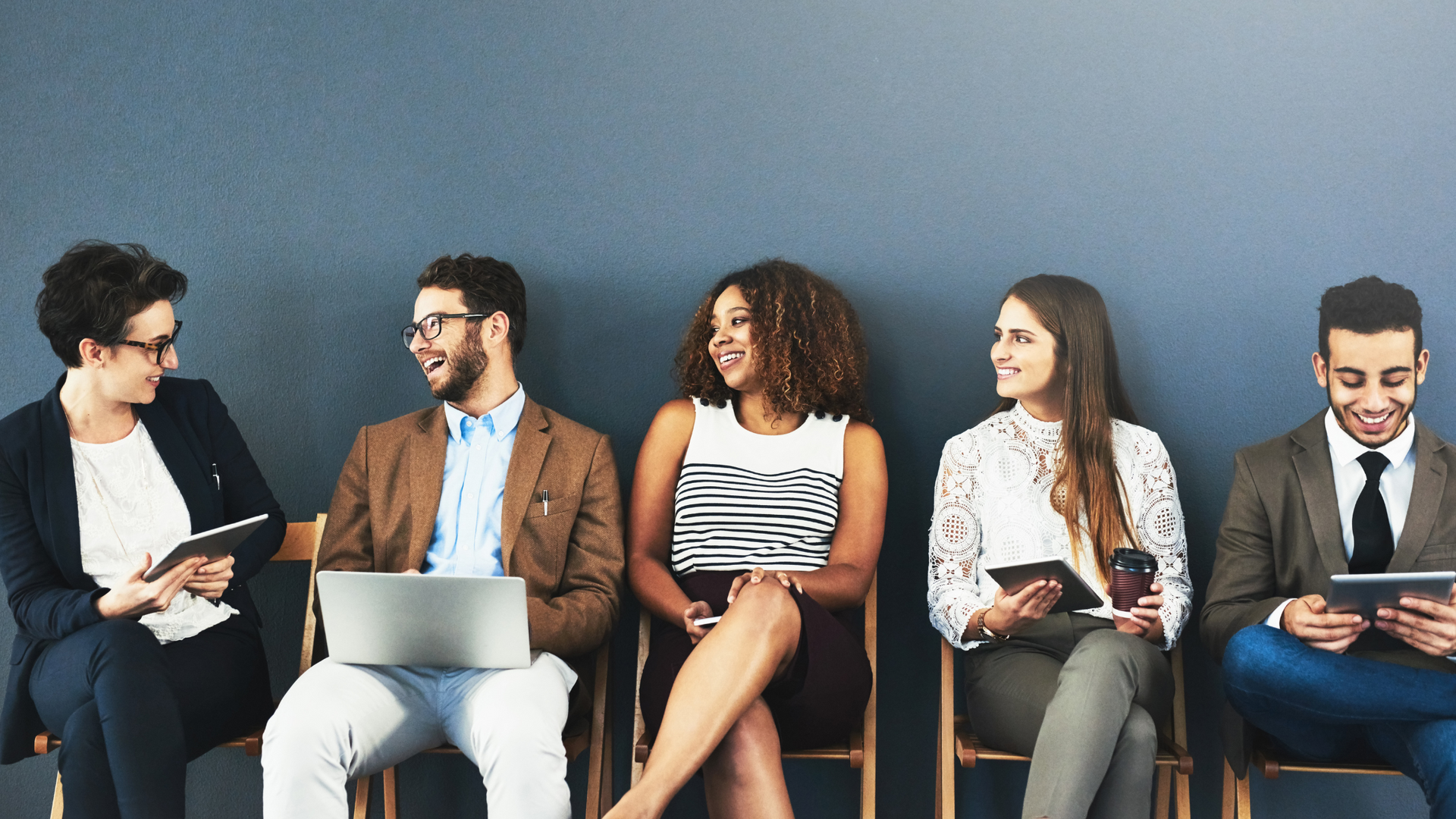 People in a work setting, sitting on chairs, interacting with each other. 