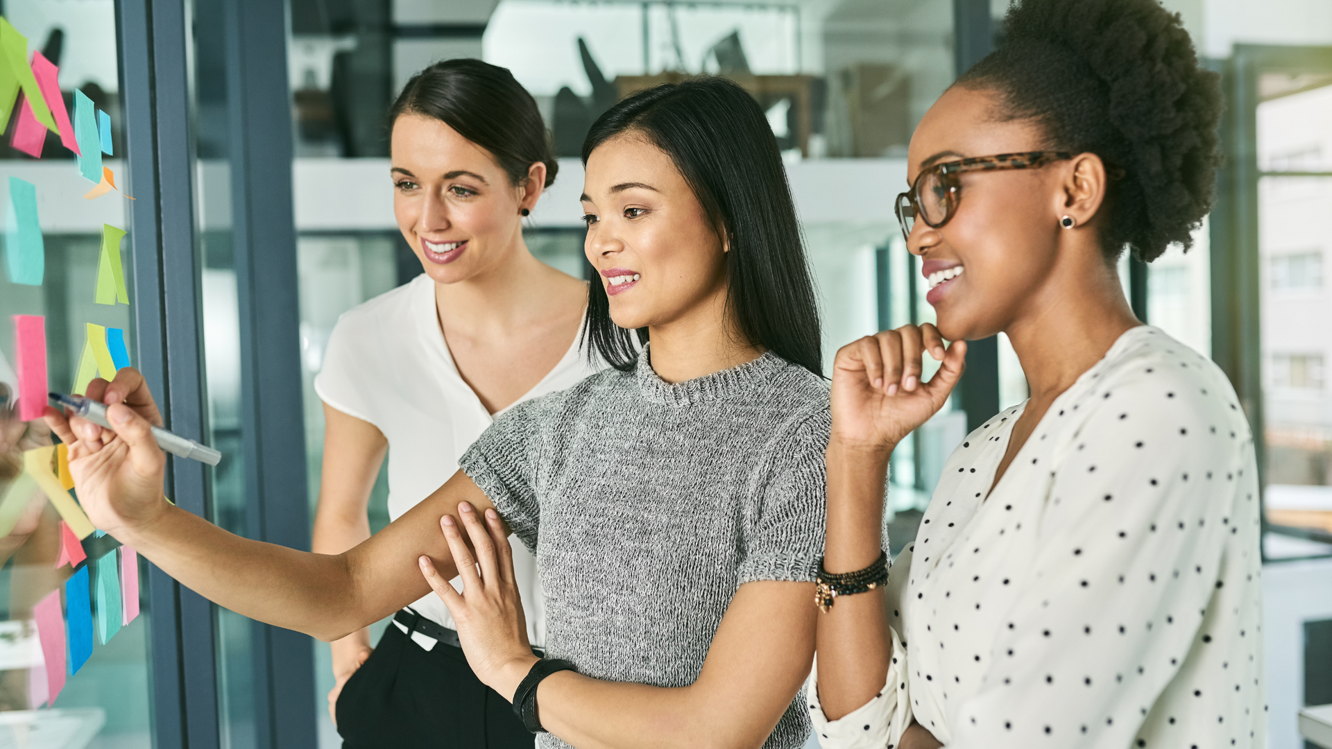 Three women in a corporate setting, strategising. 