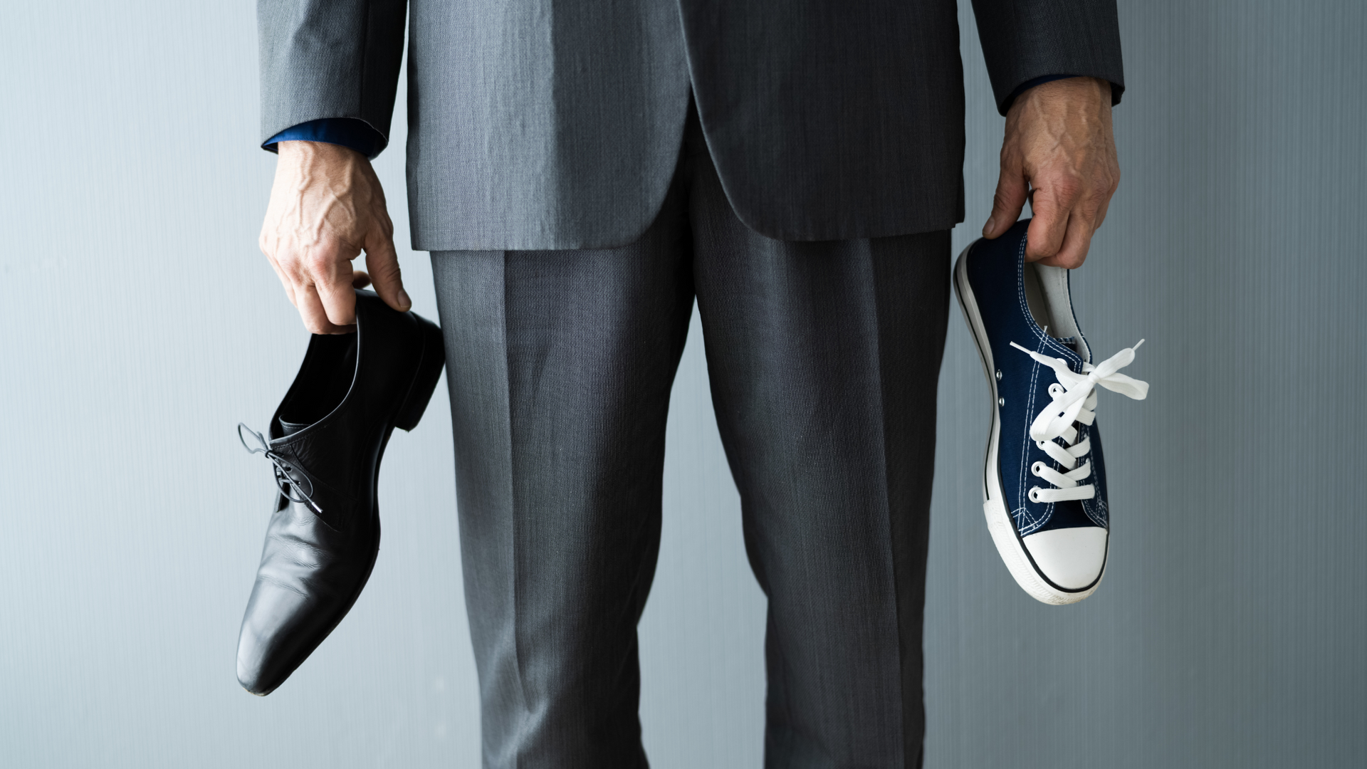 Person holding one shoe in each hand. A sneaker and a formal shoe to represent work-life balance. 