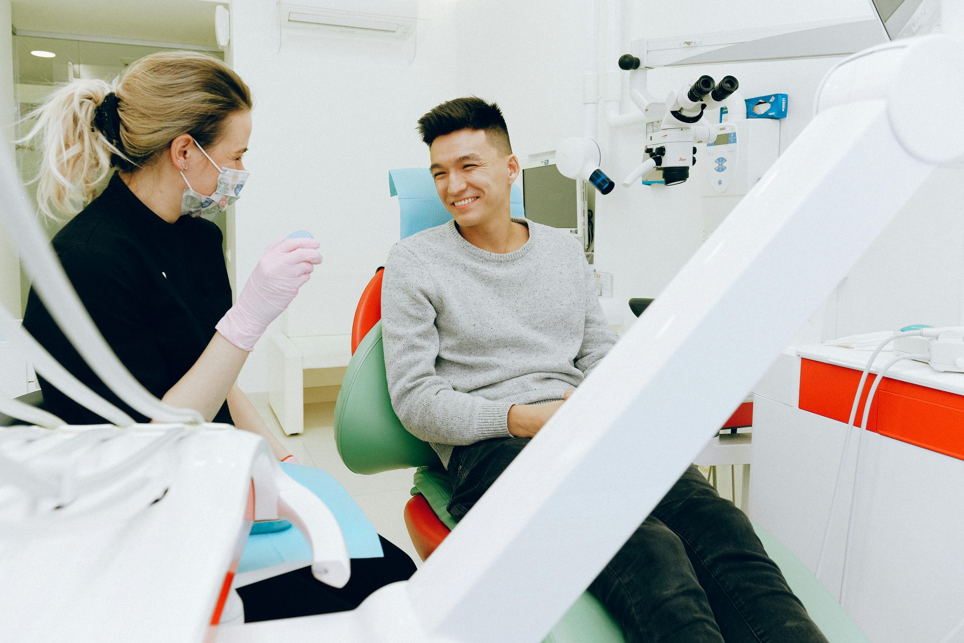 A highly professional, local photo of a dentist (wearing scrubs/lab coat) smiling with a patient.