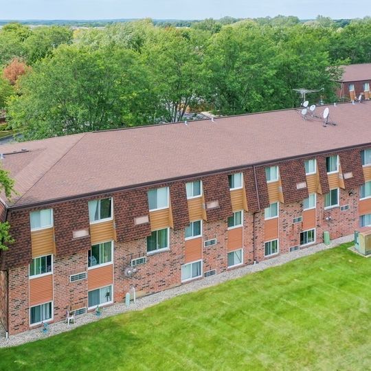 An aerial view of a large brick apartment building surrounded by trees.