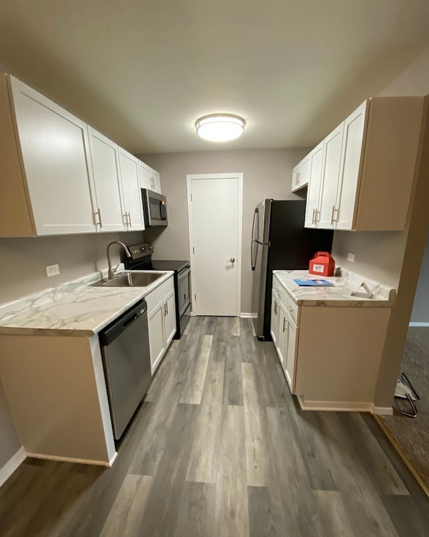 A kitchen with white cabinets , stainless steel appliances , a sink , and a refrigerator.