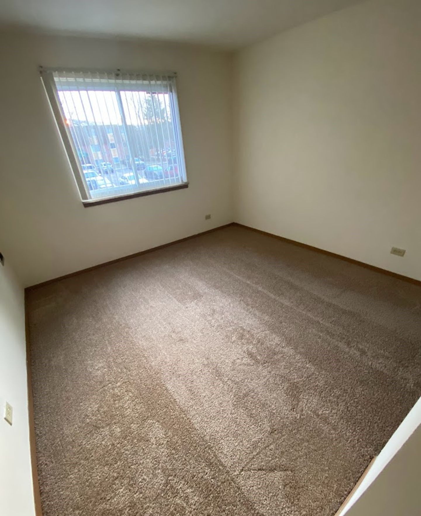 An empty room with a carpeted floor and a window.