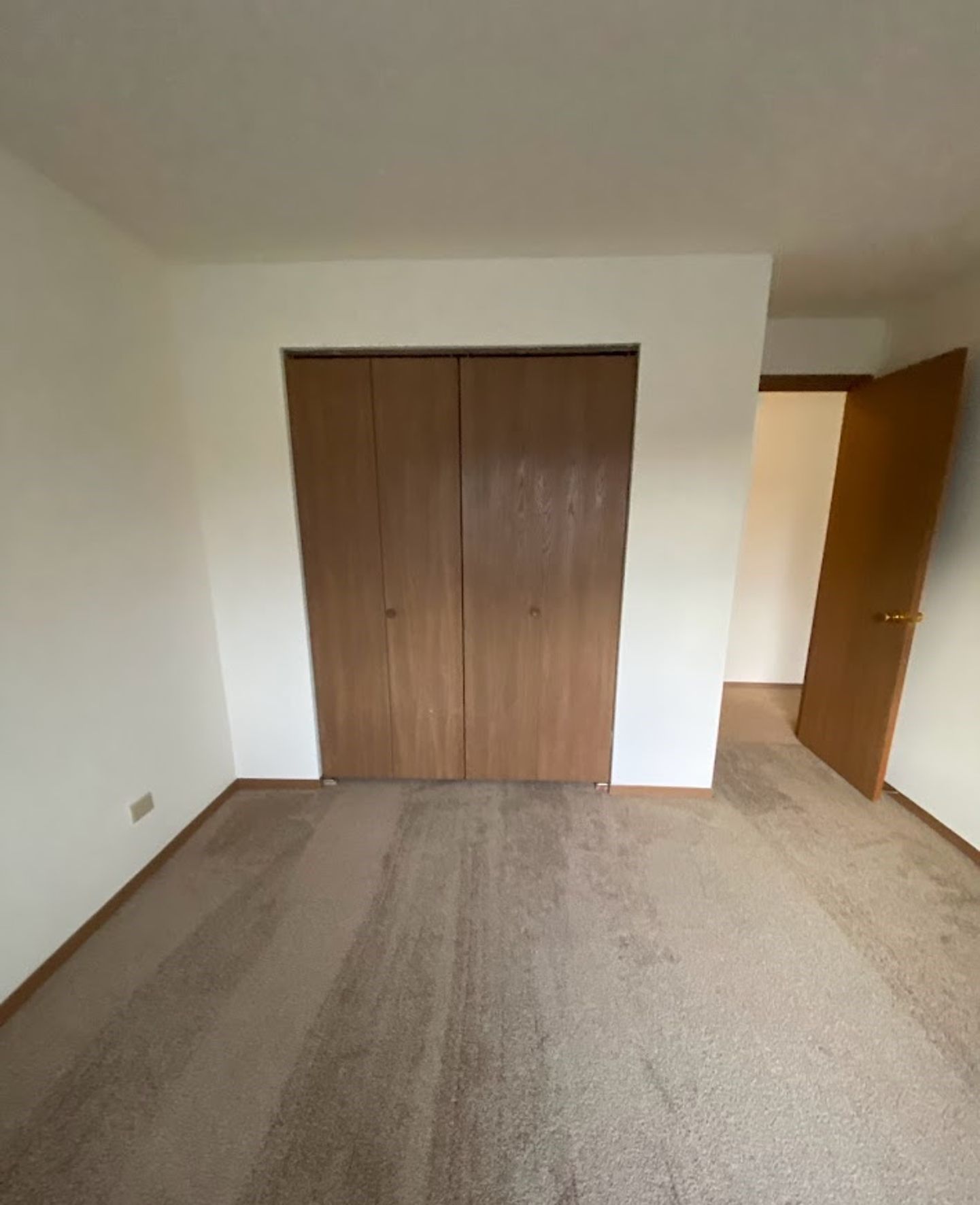 An empty bedroom with a closet and a door.