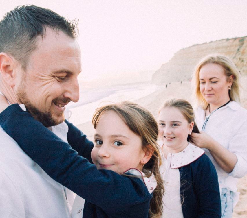 Heartwarming family lifestyle photography session on a golden beach, featuring parents and children walking hand-in-hand against a backdrop of soft Atlantic waves.