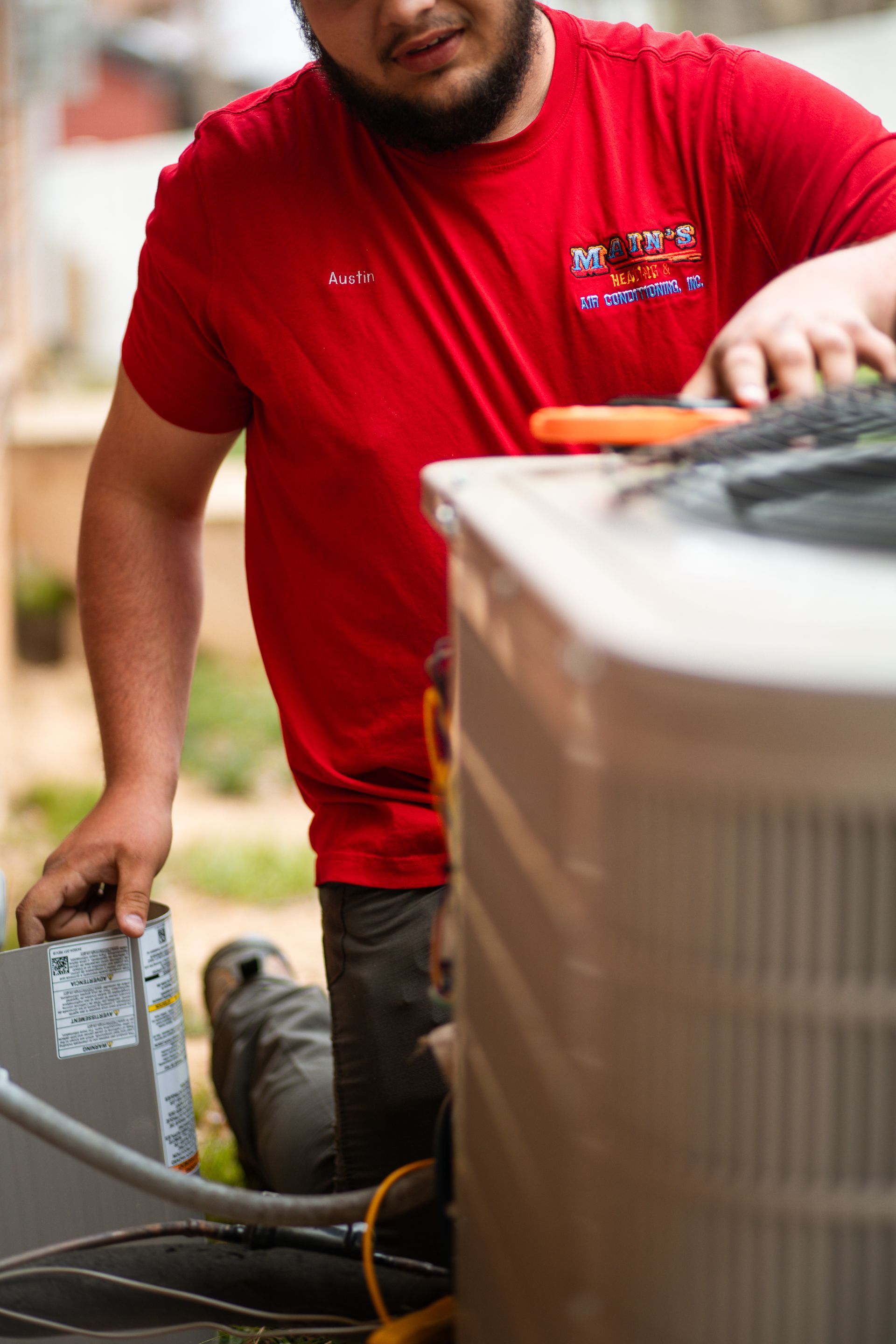 A man is using a multimeter to test an air conditioner.