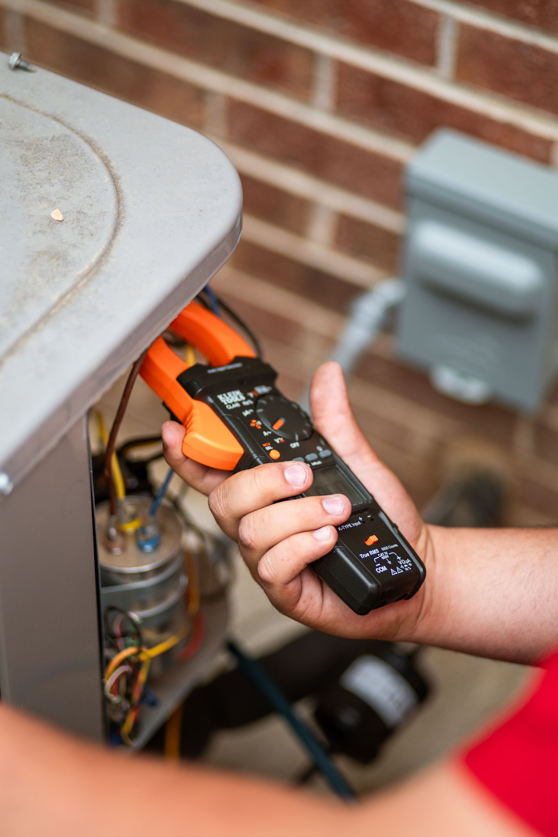 A man is using a cell phone while working on a heating system.