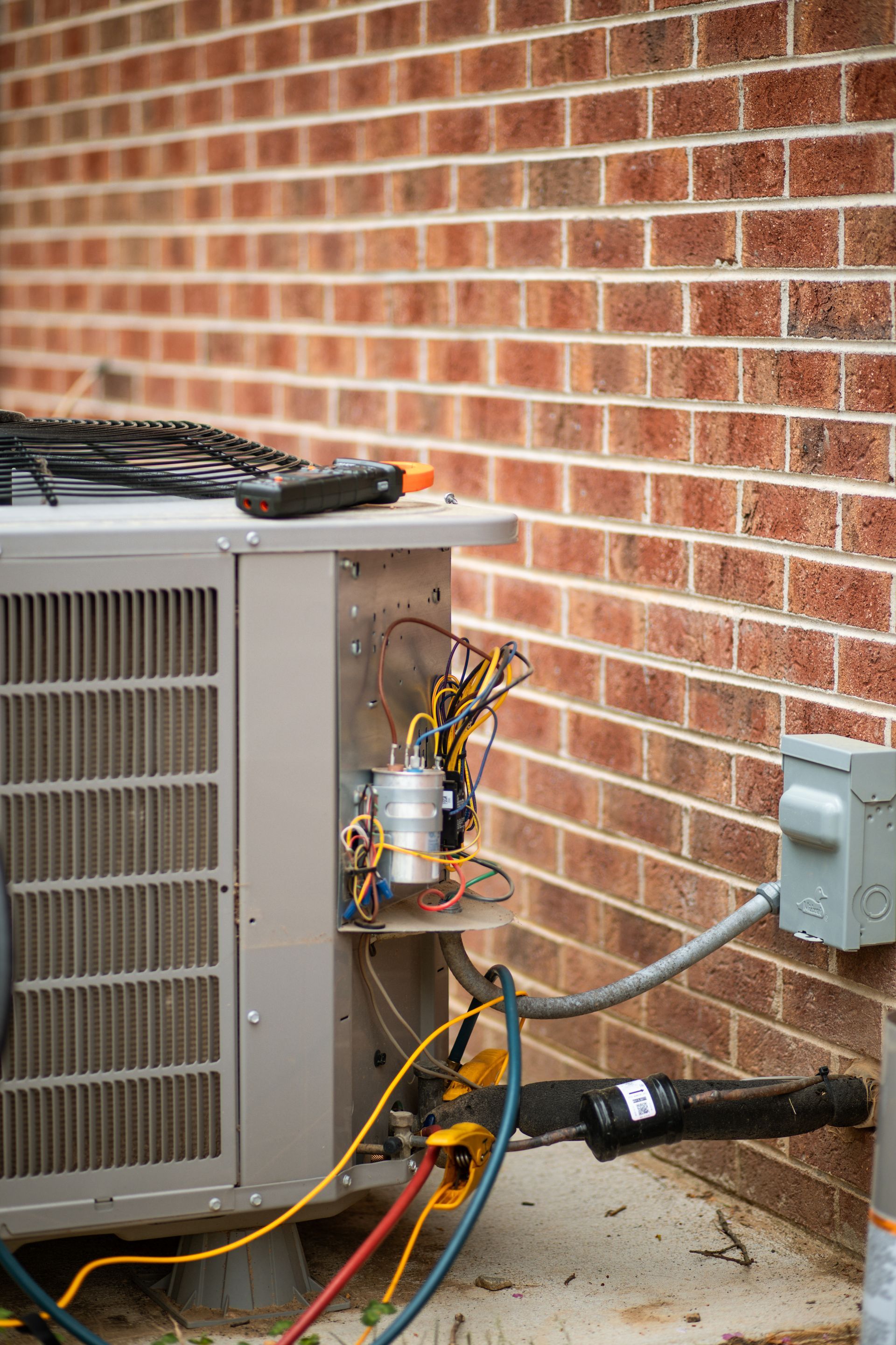 A man is working on an air conditioner with a screwdriver.
