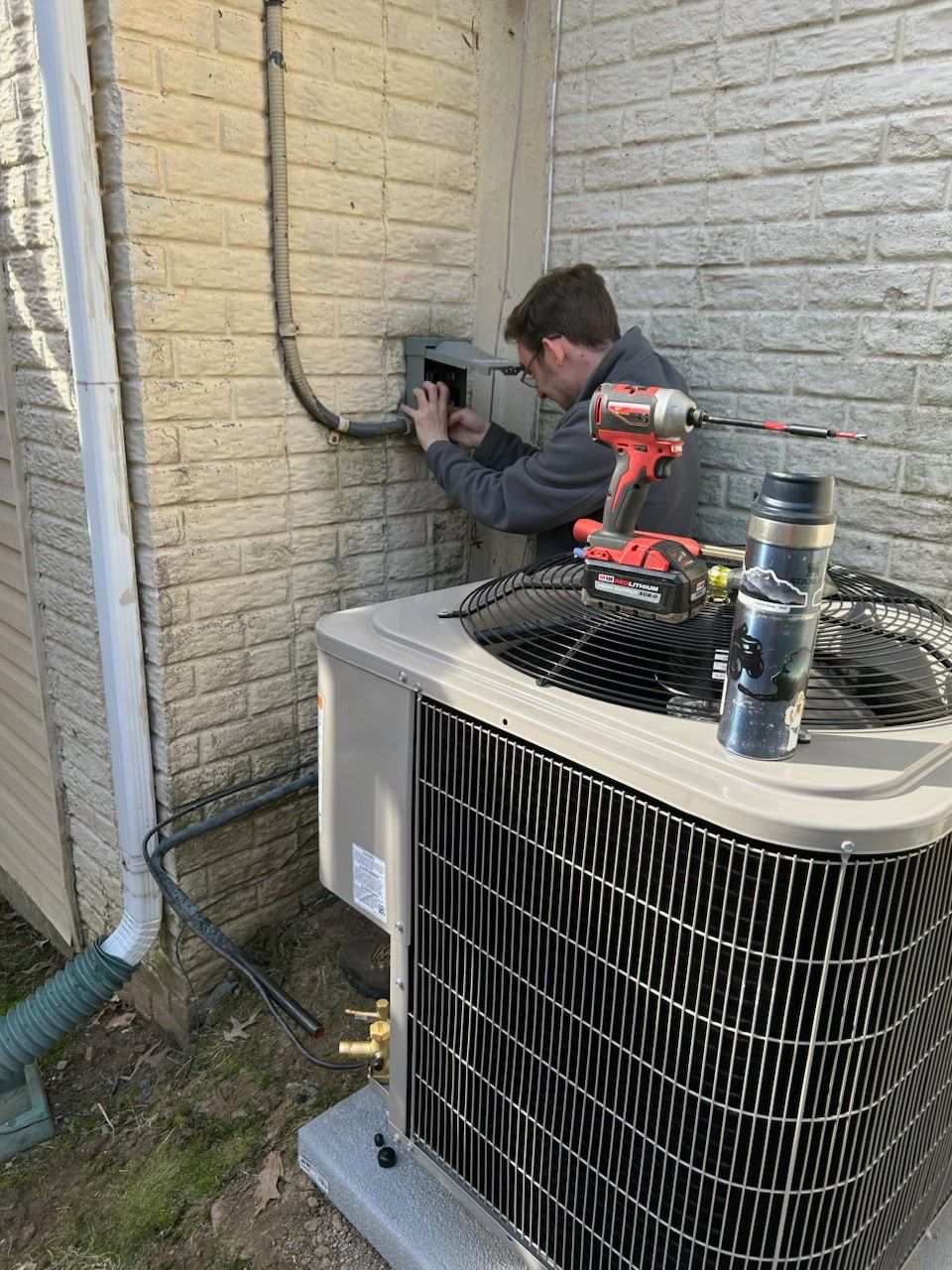 A man and a woman are standing next to an air conditioner.